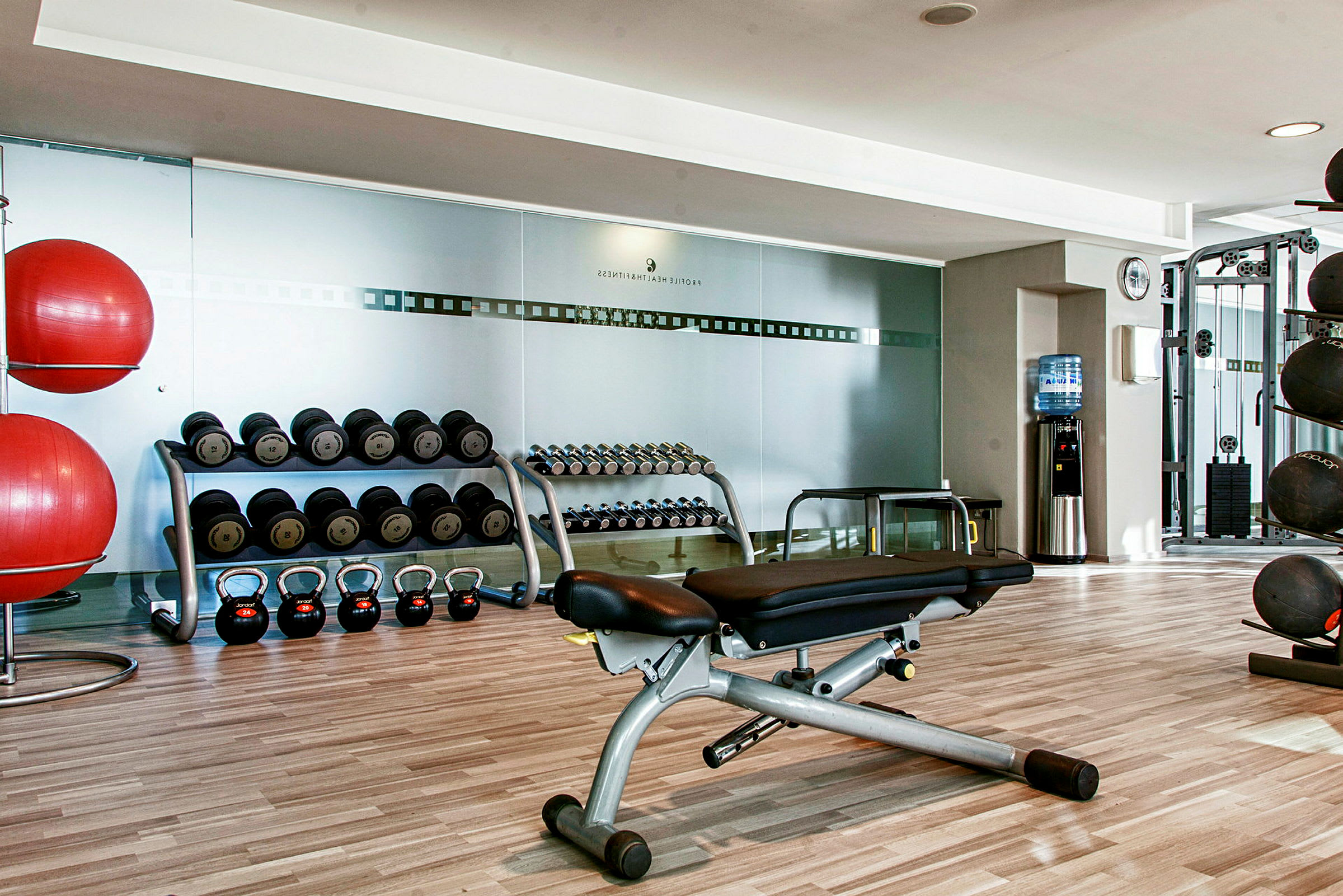 Et fitnesscenter med vægte, træningsbænke, kettlebells og træningsbolde. (AI-genereret tekst)