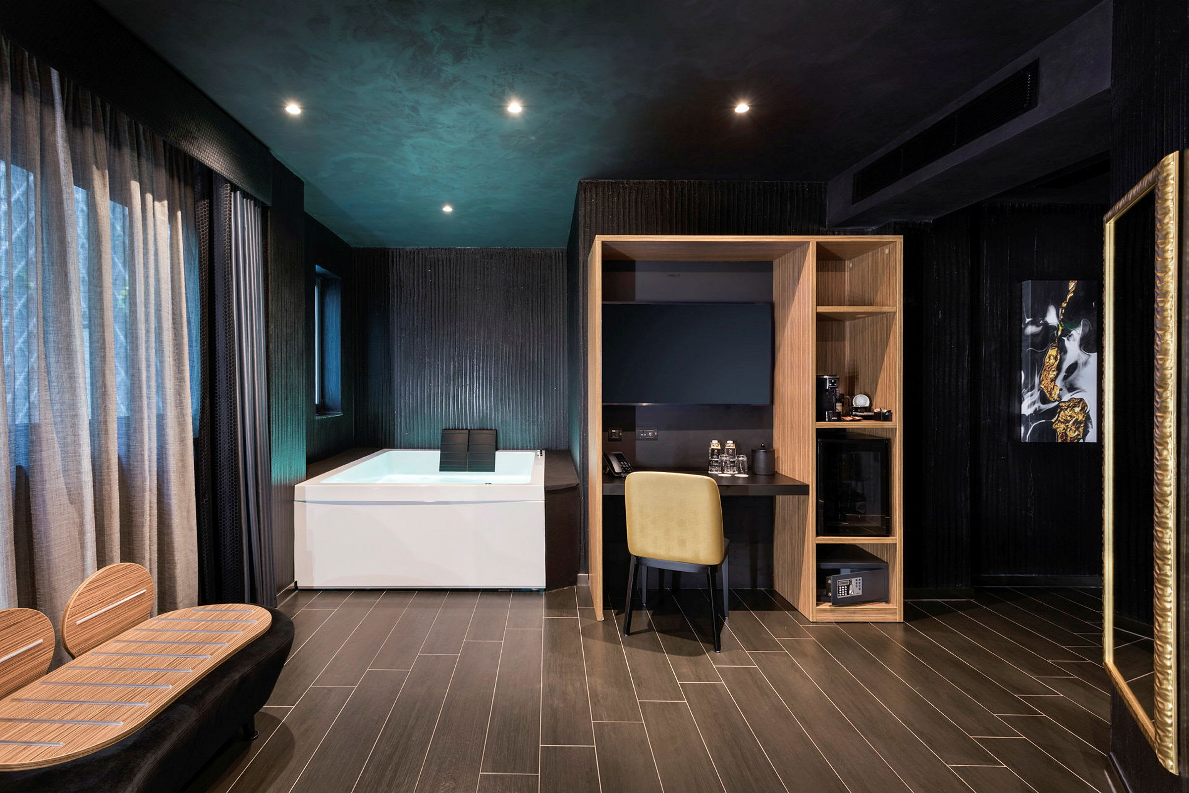 Et moderne hotelværelse med mørke vægge, et hvidt badekar, et skrivebord med en gul stol og en træhylde. (AI-genereret tekst)