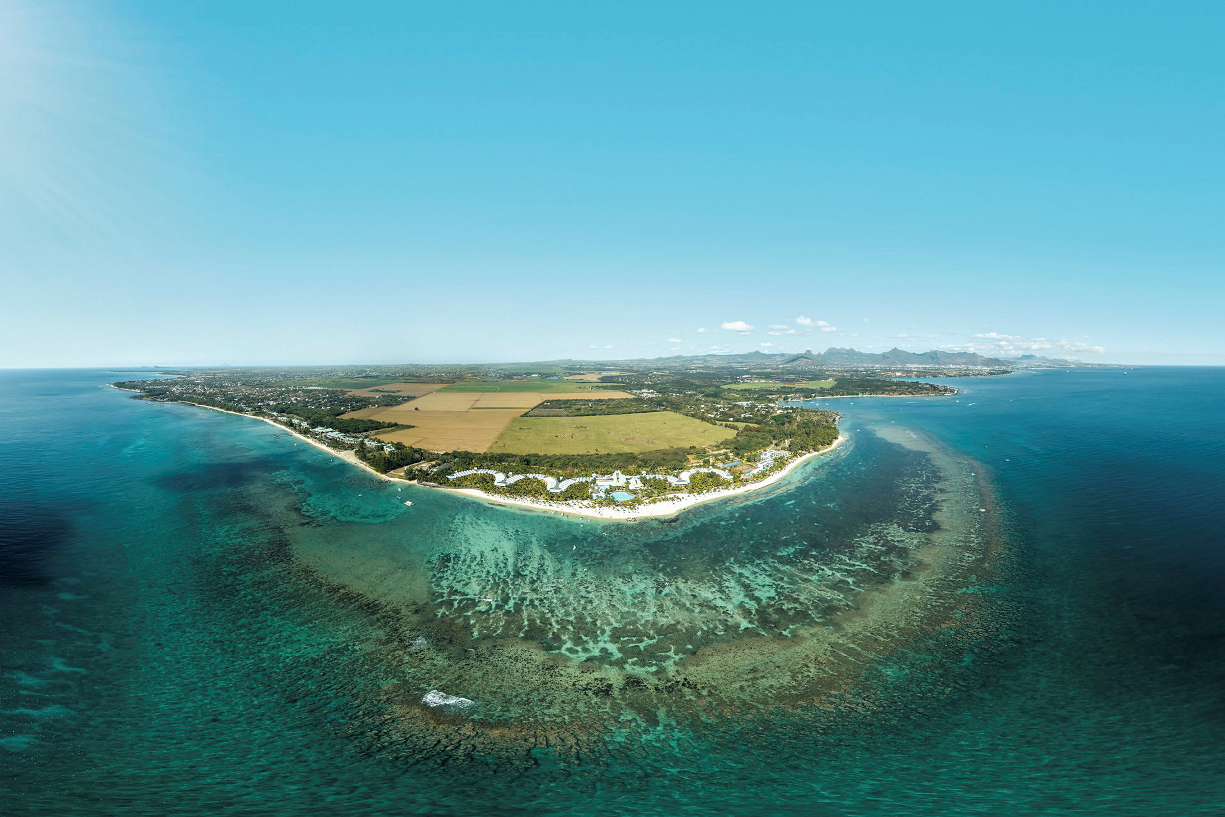 Luftfoto af en kyst med turkis vand, sandstrande og omkringliggende landskab. (AI-genereret tekst)