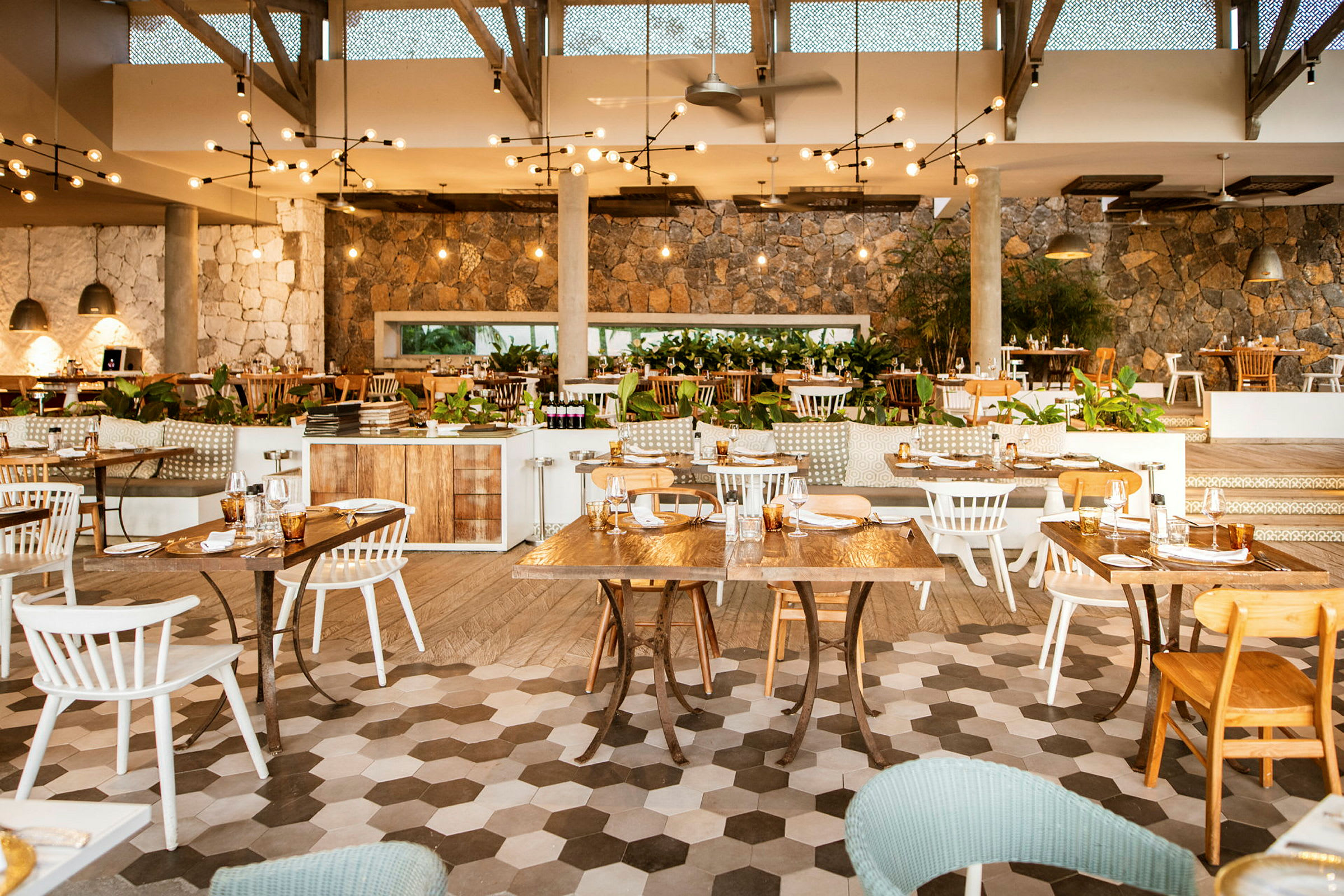 En restaurant med træborde og stole, dekoreret med lyskæder og planter. (AI-genereret tekst)