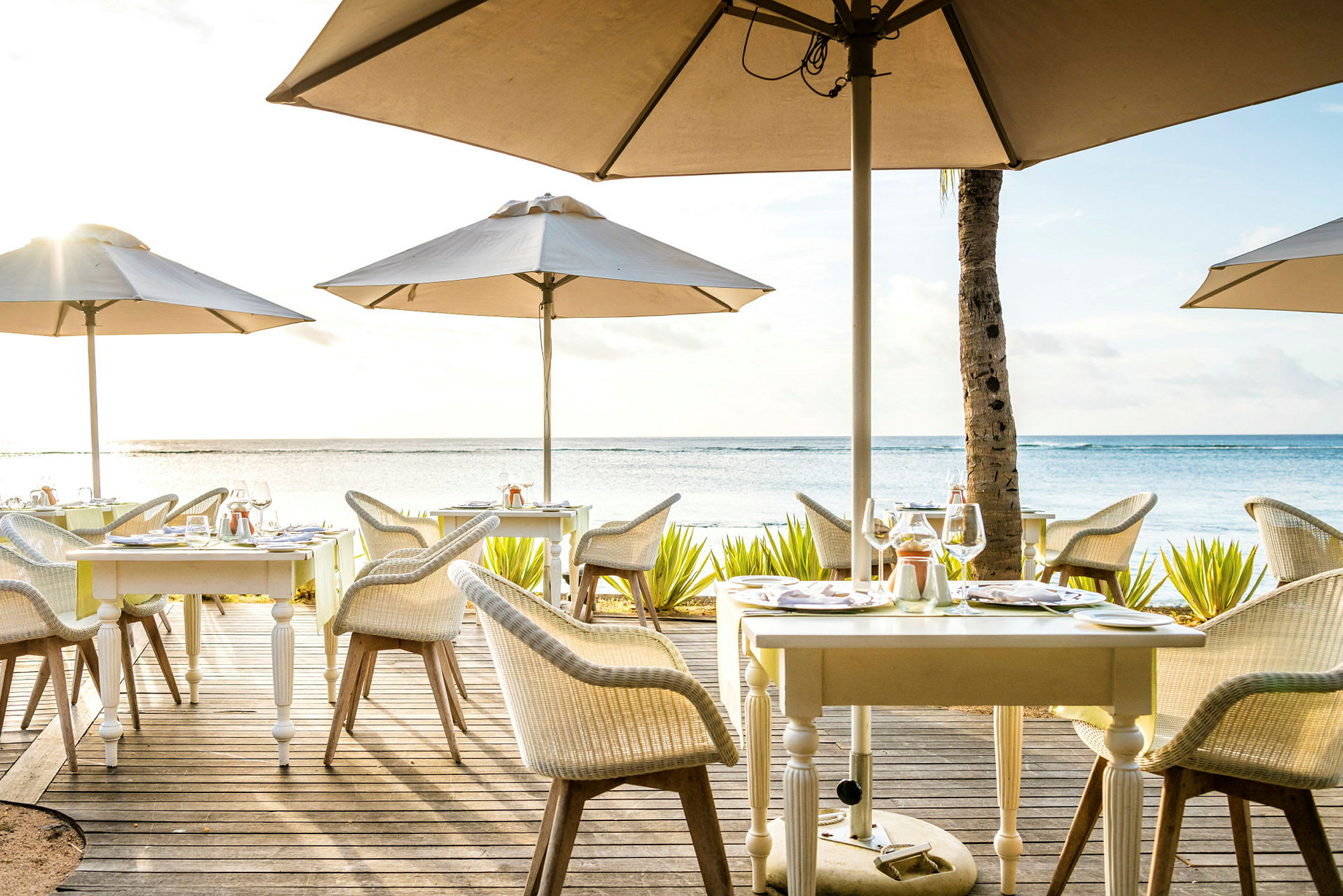 En udendørs restaurant med borde og parasoller ved havet. (AI-genereret tekst)