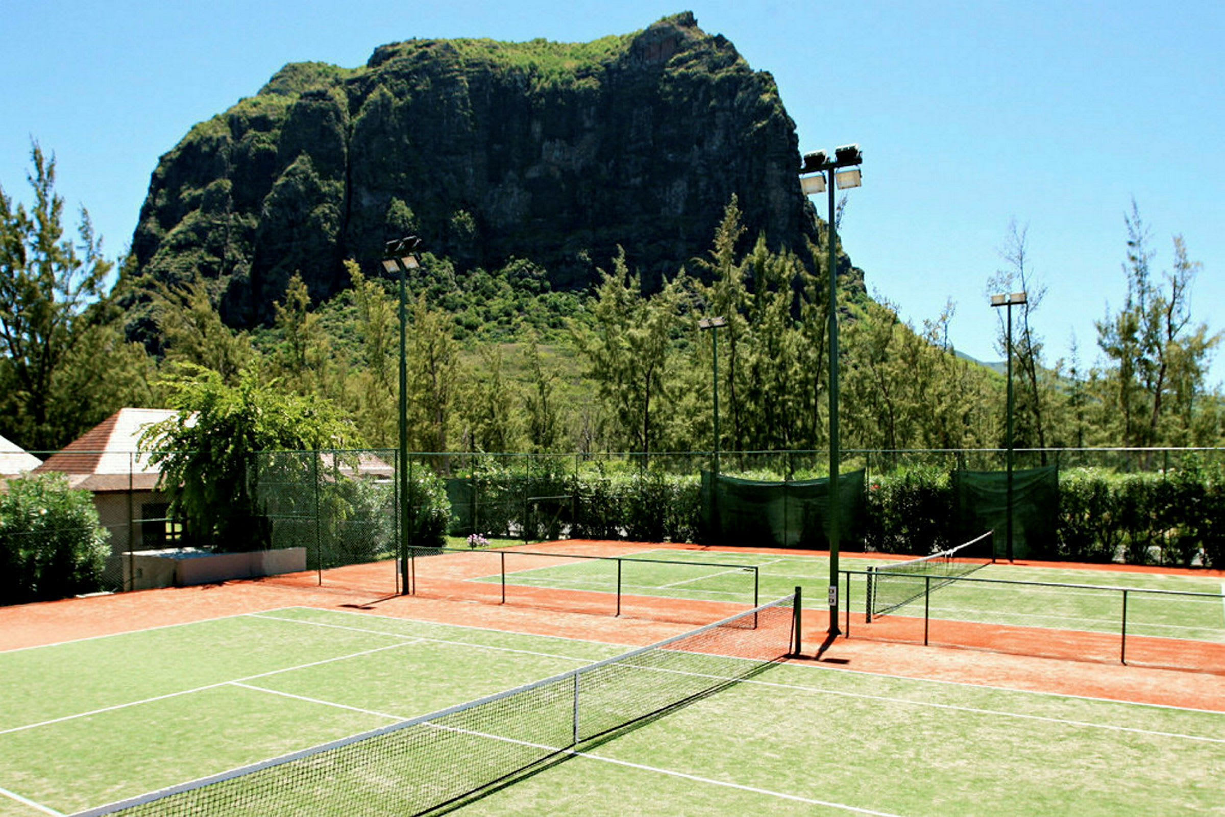 Tennisbaner foran en stor klippe. (AI-genereret tekst)