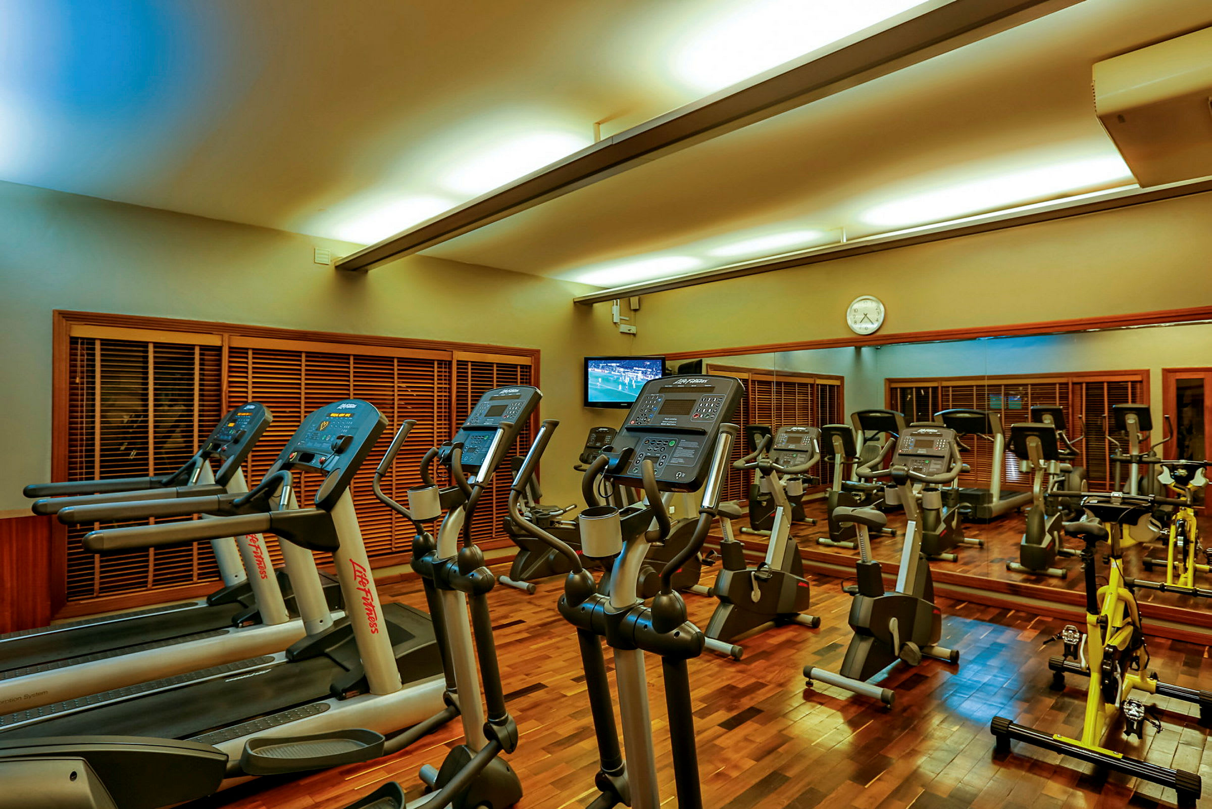 Et fitnesscenter med træningsmaskiner, herunder løbebånd, motionscykler og træningsudstyr. (AI-genereret tekst)