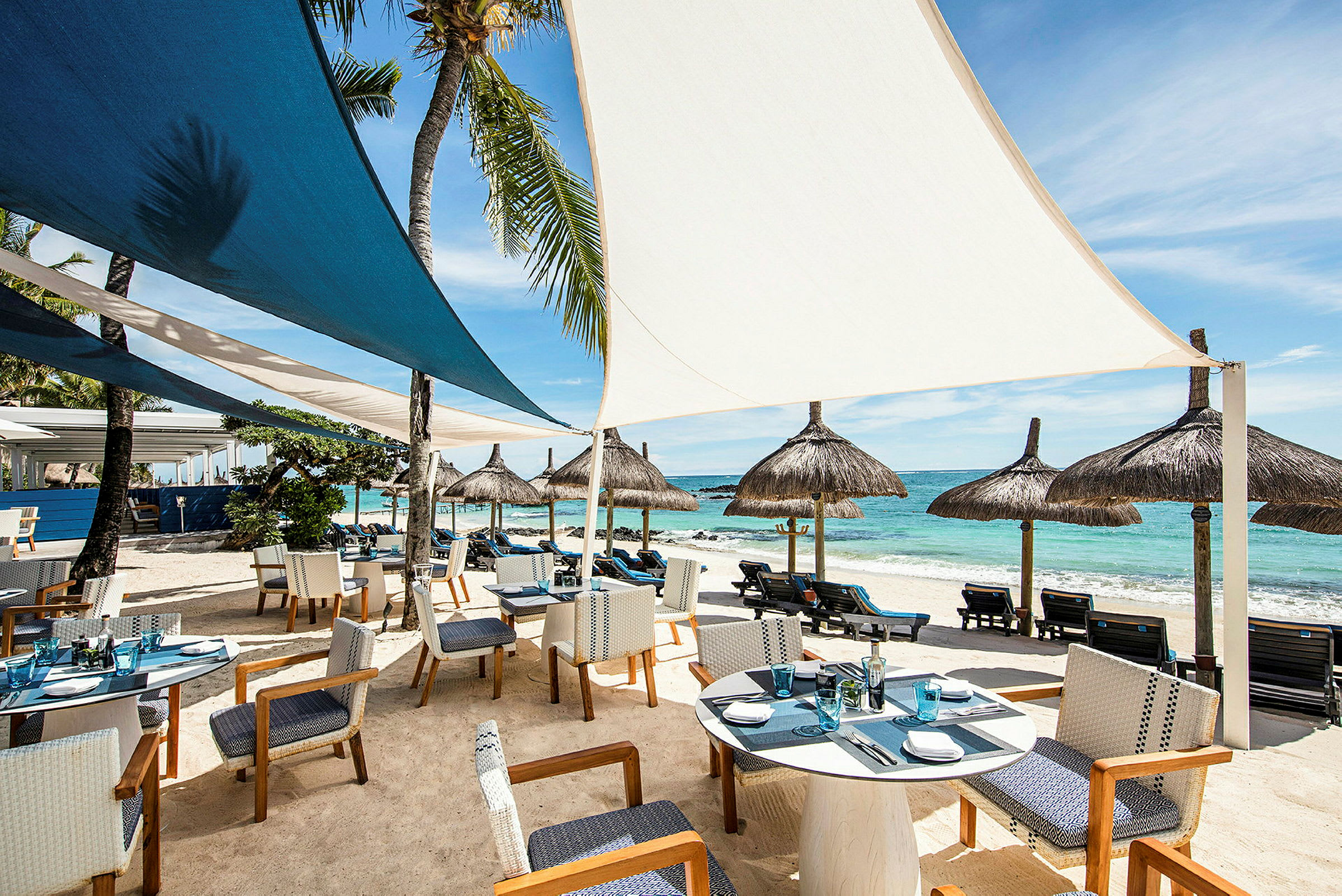 Restaurant ved stranden med siddepladser og parasoller. (AI-genereret tekst)