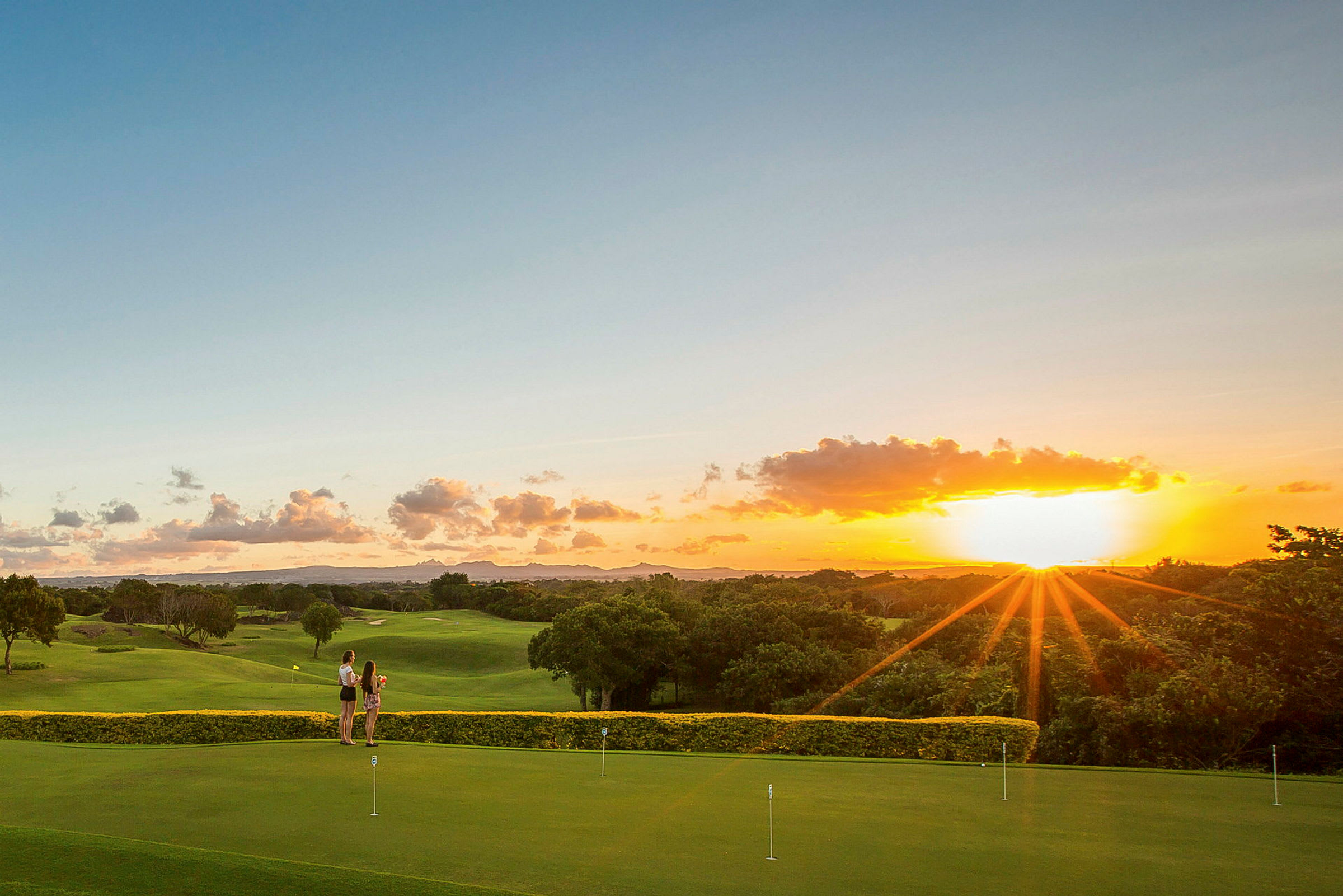 To personer står på en golfbane ved solnedgang. (AI-genereret tekst)