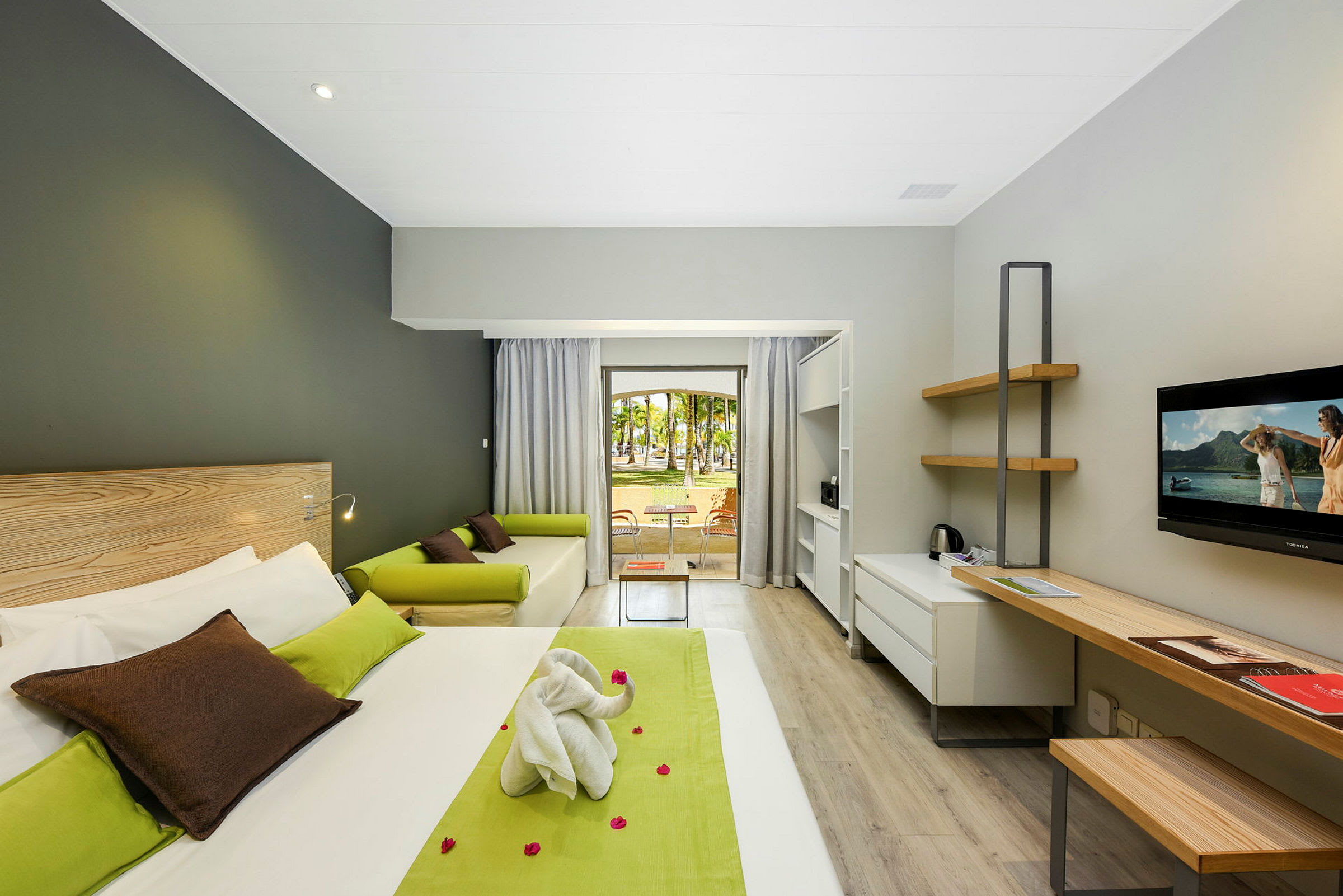 Moderne hotelværelse med seng, skrivebord, sofa og udsigt til en have. (AI-genereret tekst)