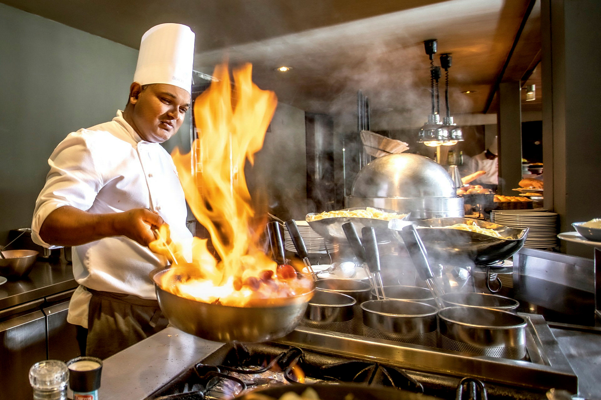 En kok, der laver mad med flambé i et køkken. (AI-genereret tekst)