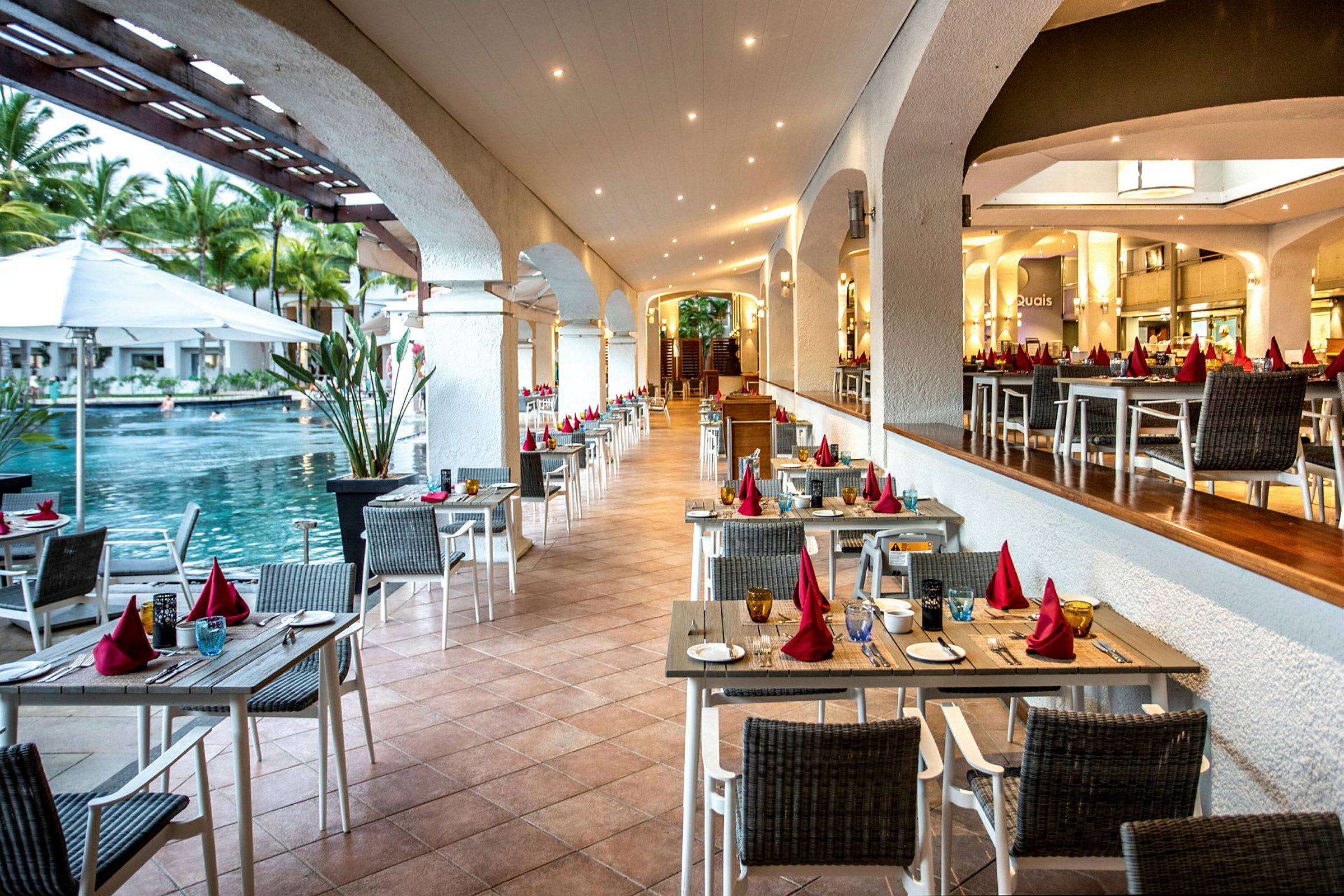 Restaurant med borde og stole tæt på en pool. (AI-genereret tekst)