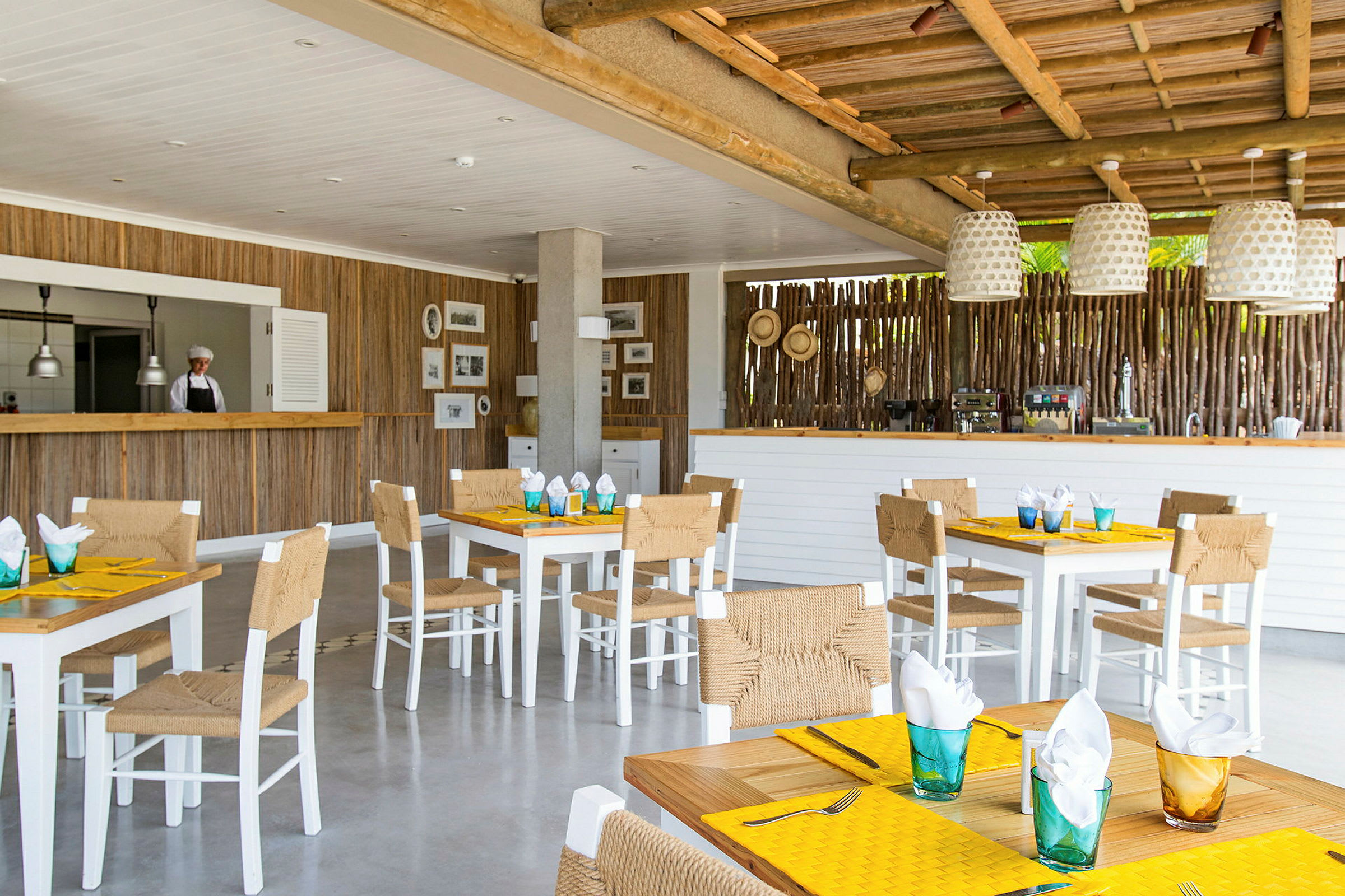 En restaurant med træindretning, hvide borde og stole, og opdækkede borde. (AI-genereret tekst)
