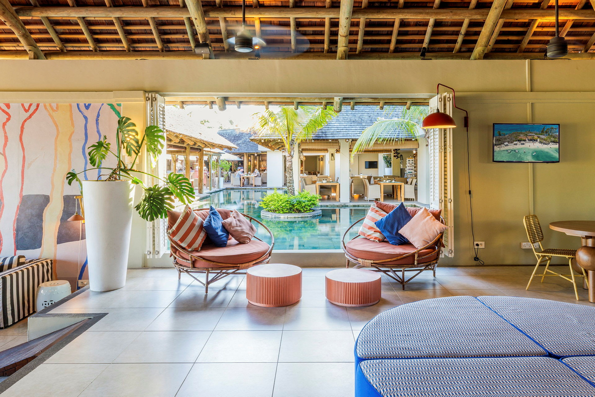 Lounge møbler med puder i et indendørsmiljø ved siden af en pool. (AI-genereret tekst)