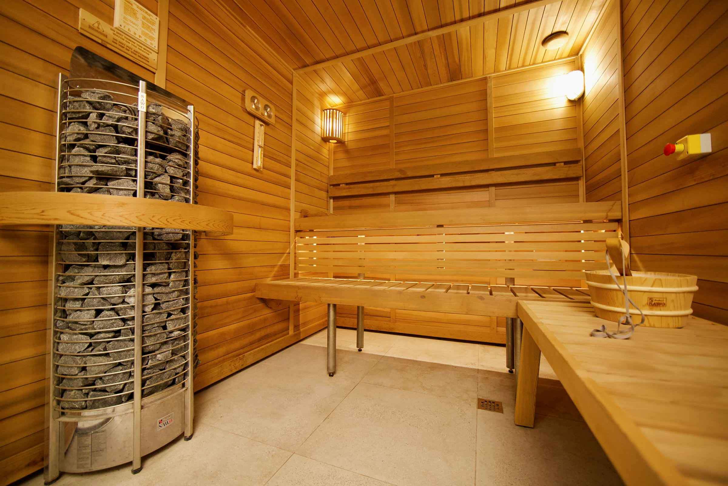 Billedet viser et interiør af en finsk sauna med træpanelvægge, en bænk og en saunaovn med sten. (AI-genereret tekst)