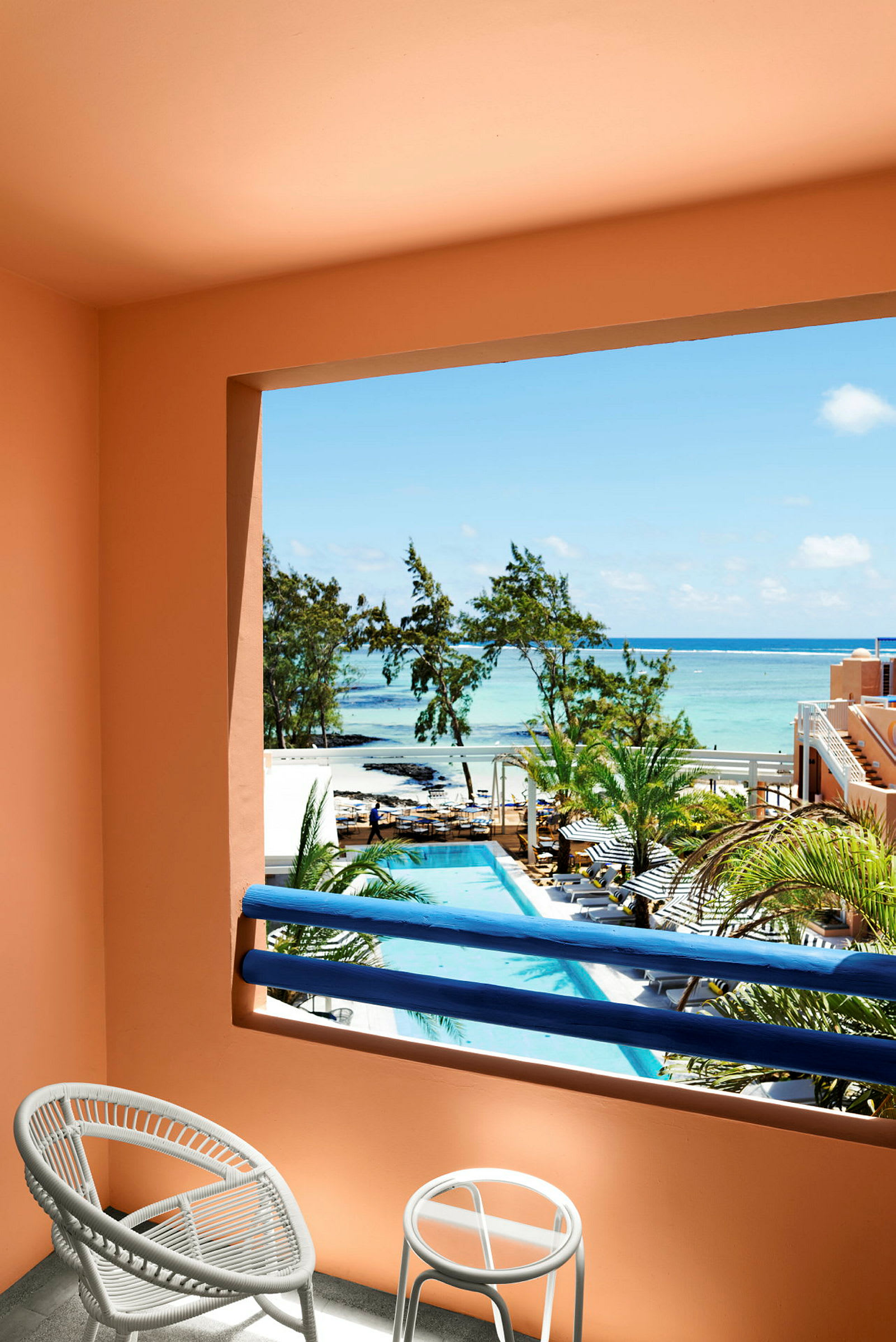 Udsigt fra en balkon med stole, over en pool og mod havet. (AI-genereret tekst)