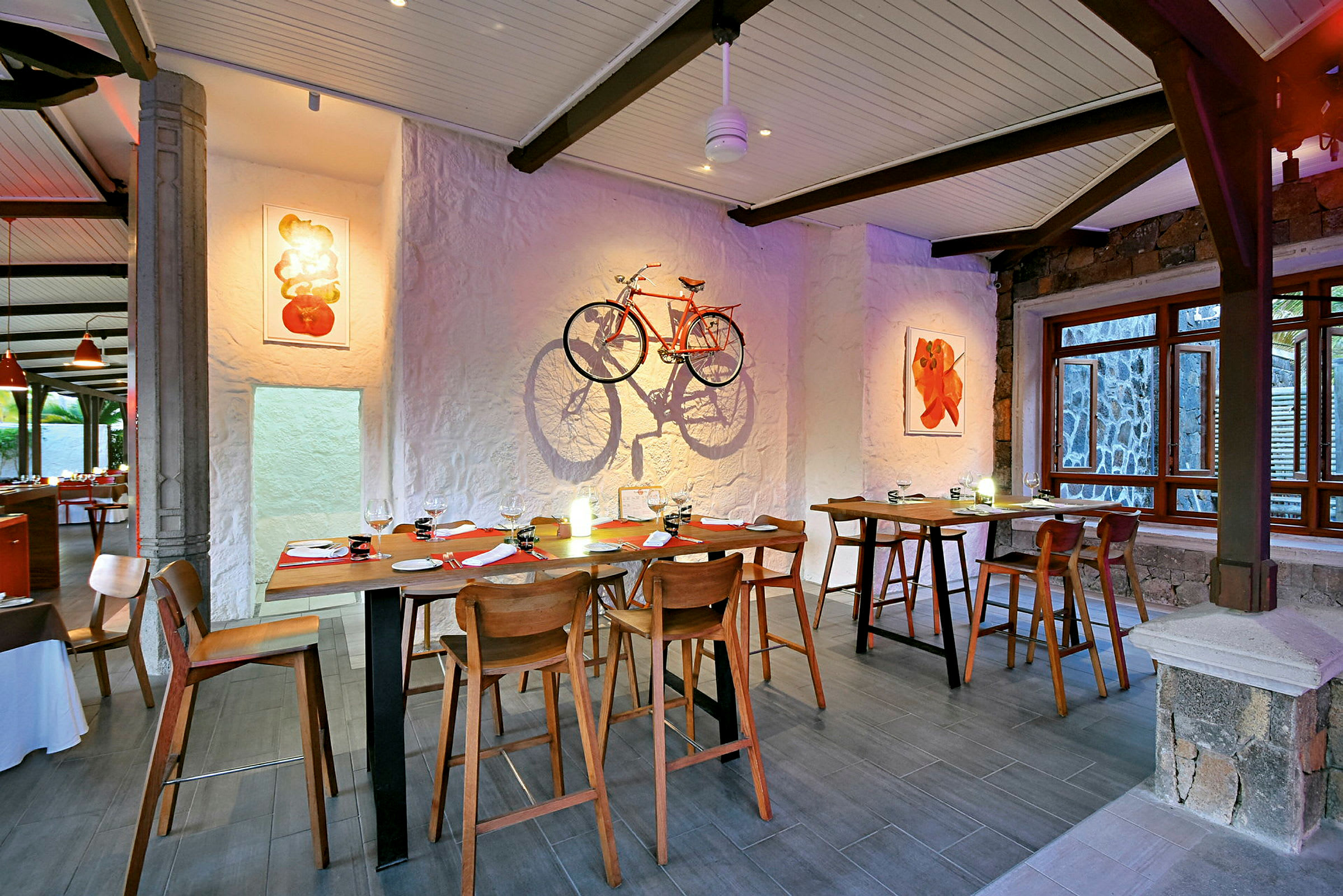 Indretning af restaurant med træborde og stole, kunst på væggene og en orange cykel dekoreret som vægkunst. (AI-genereret tekst)