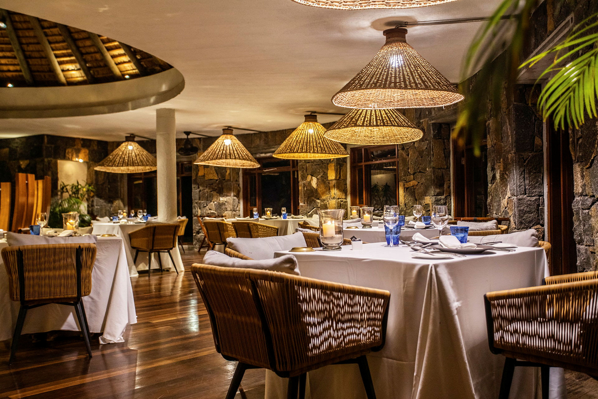 En elegant restaurant med dækkede borde og rottinglamper. (AI-genereret tekst)