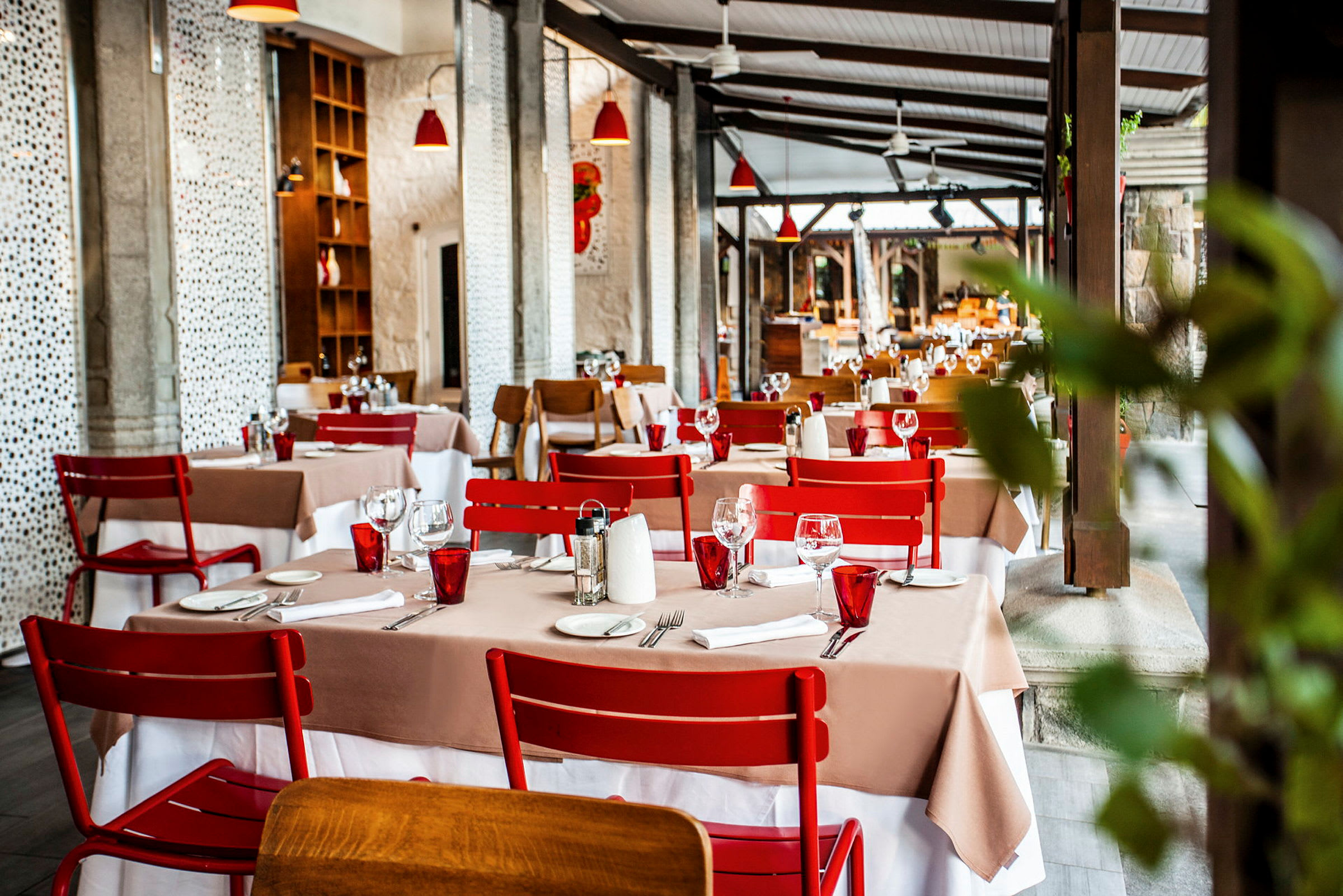 Restaurant med dækkede borde og røde stole. (AI-genereret tekst)