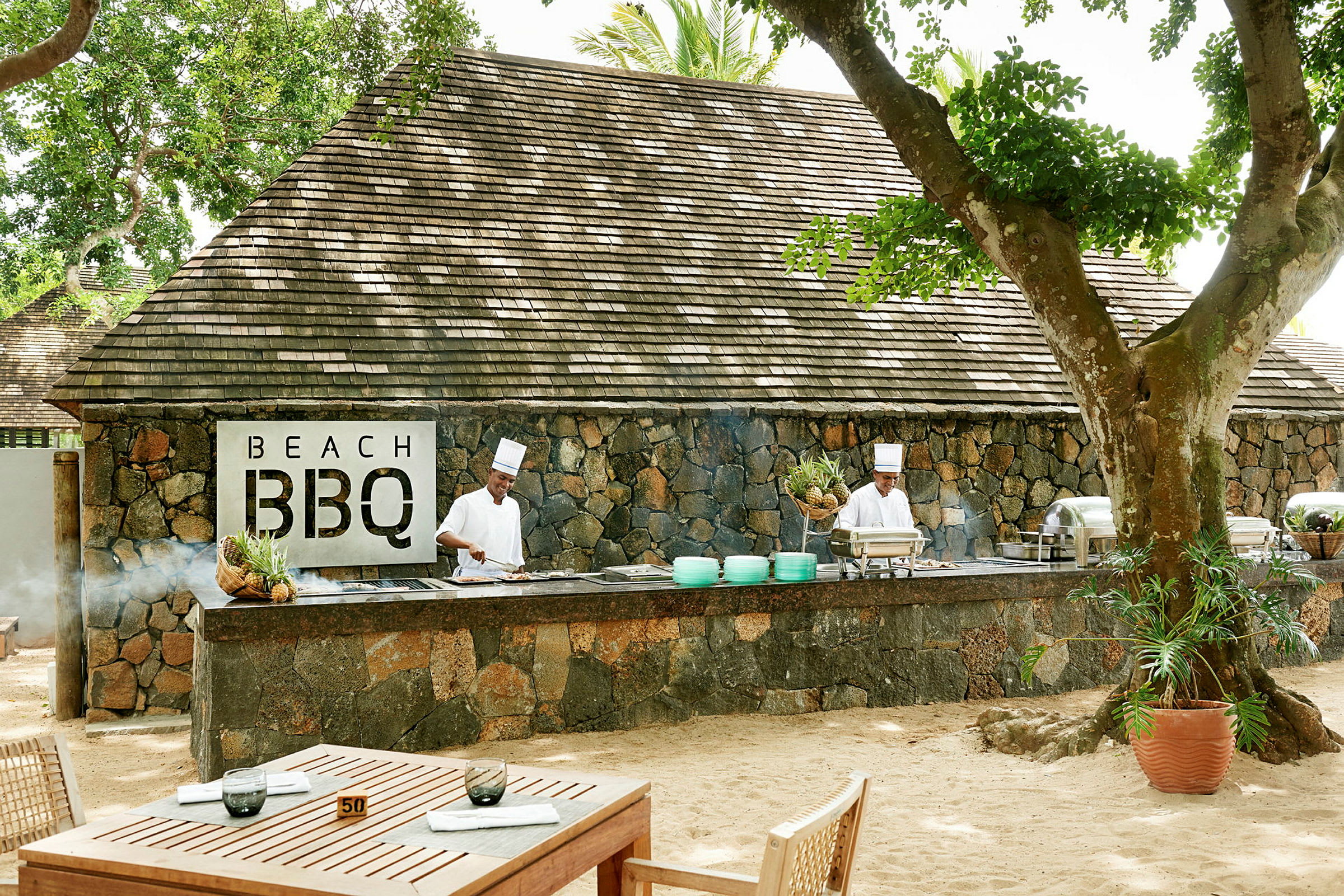 Billede af en udendørs servering med stenbygning og BBQ-område. (AI-genereret tekst)