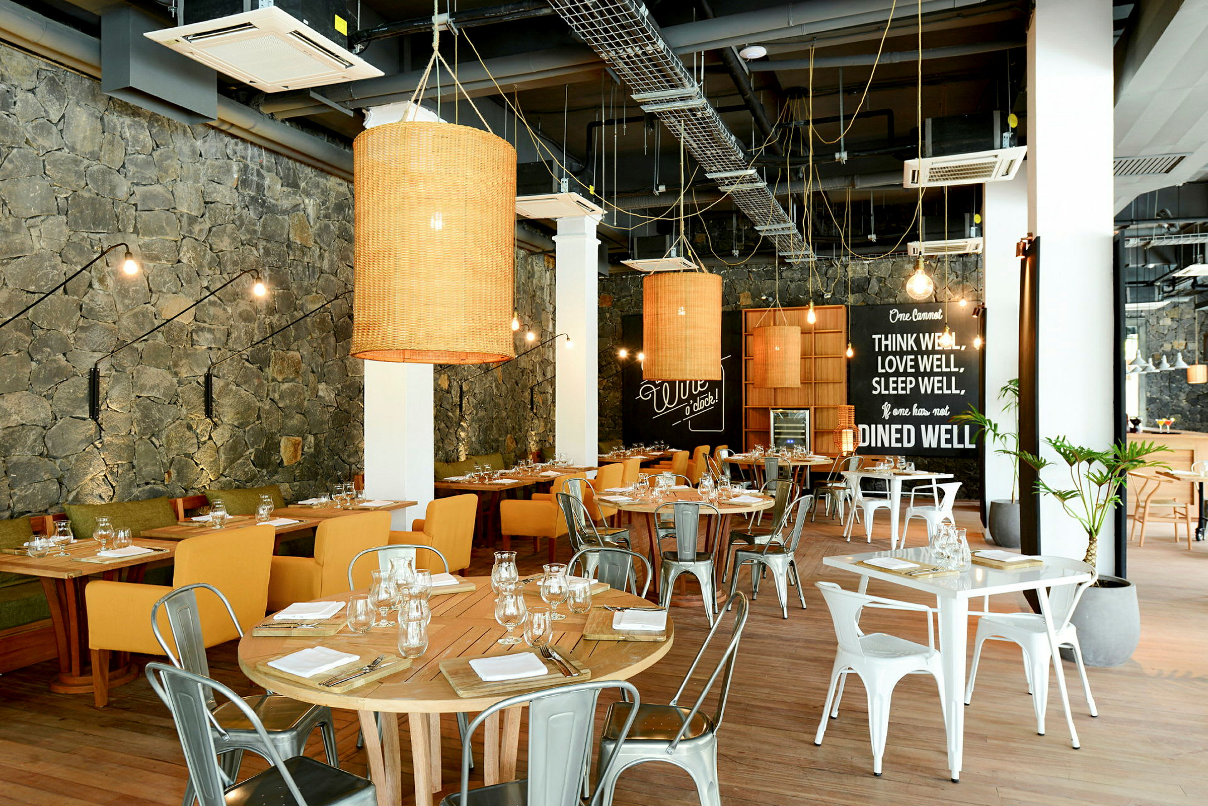 En indendørs restaurant med træborde og stole, dekoreret med væglamper og store lamper. (AI-genereret tekst)