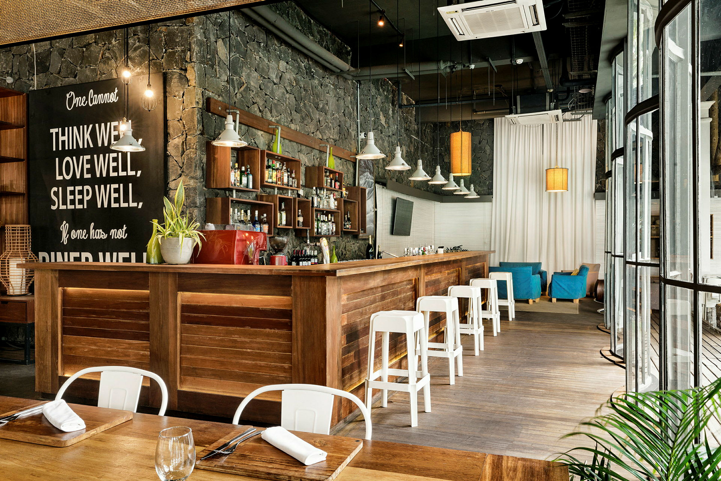 En indretning af en moderne bar med træinteriør, hvide stole og en stenmur. (AI-genereret tekst)