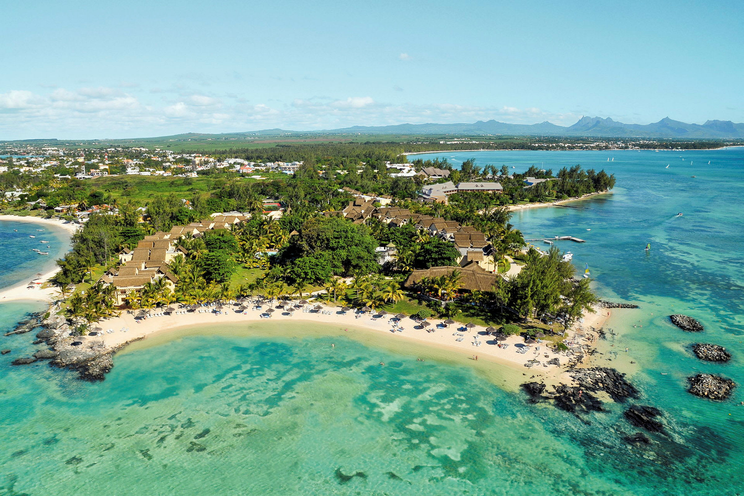 Luftfoto af et tropisk resort ved en strand med turkisfarvet vand. (AI-genereret tekst)