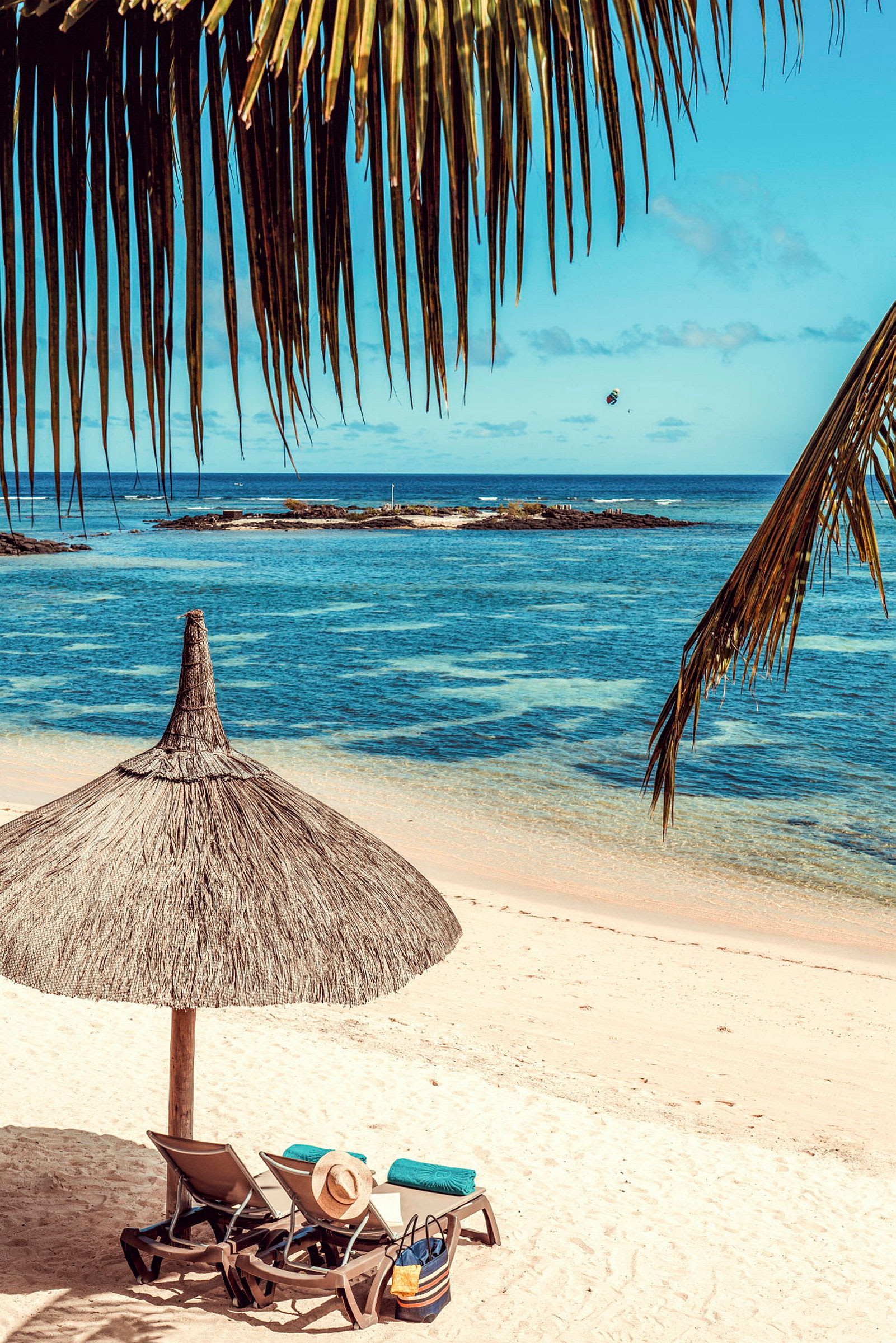 Liggestole under en parasol på en sandstrand ved havet. (AI-genereret tekst)