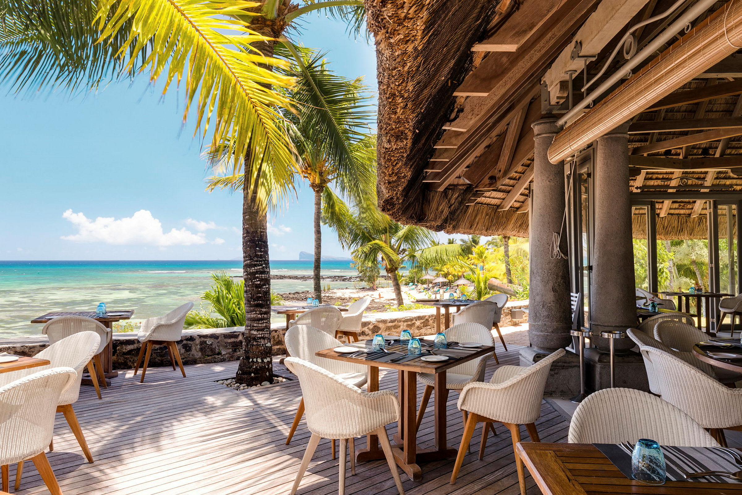 En strandrestaurant med siddepladser udendørs og udsigt over havet. (AI-genereret tekst)