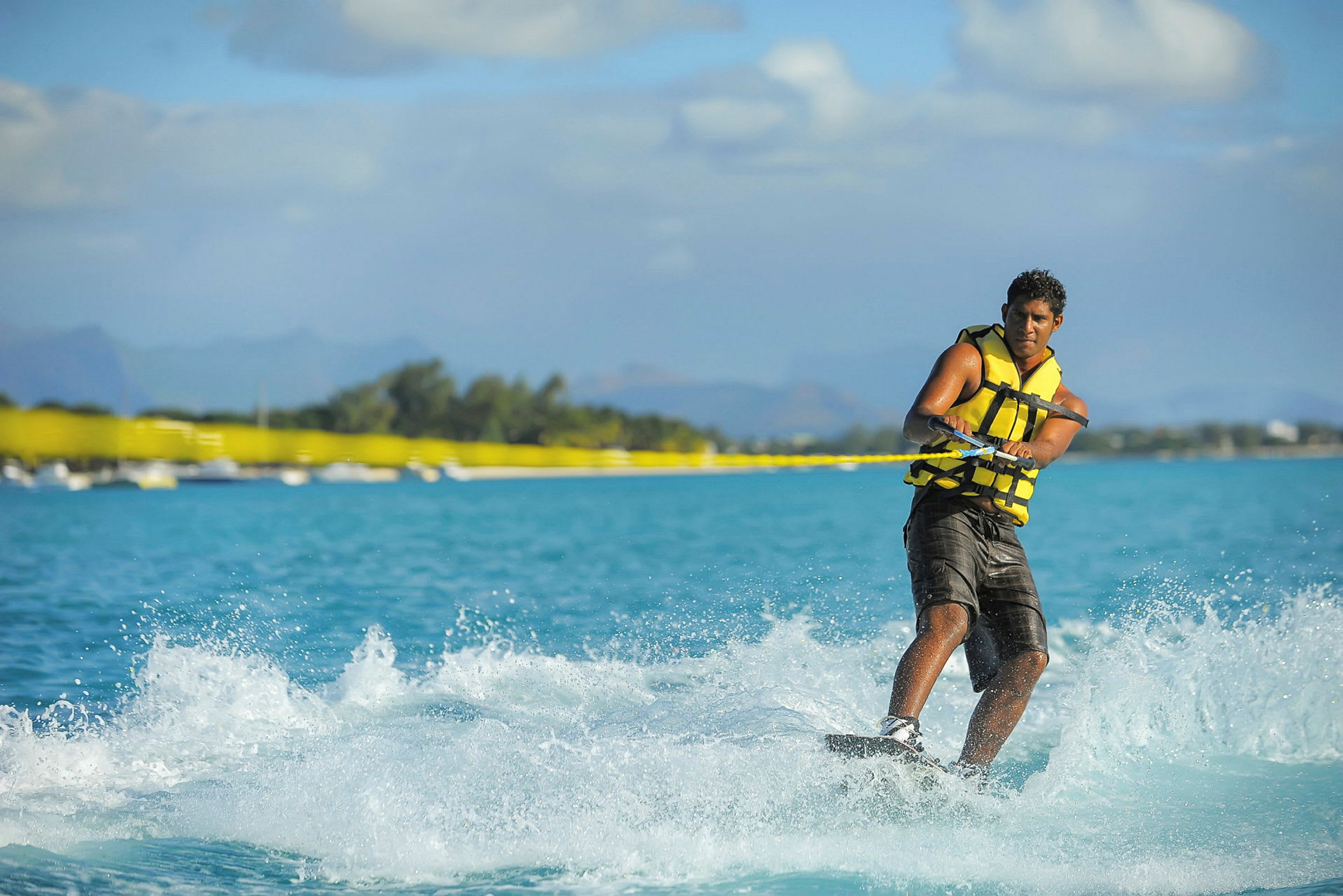 Person wakeboarder på blåt vand, bjerge i baggrunden. (AI-genereret tekst)