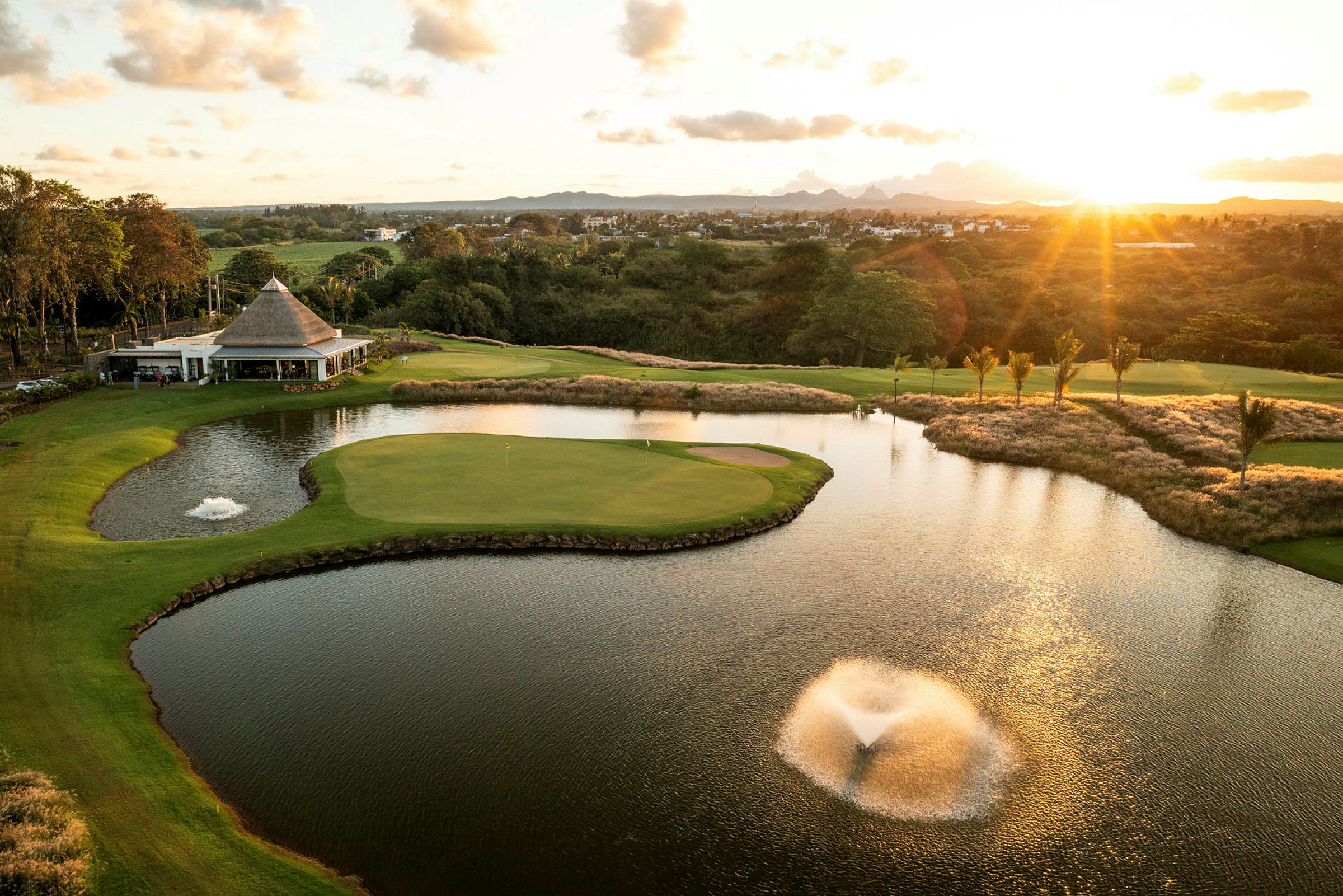 Golfbane med en dam og springvand under en solnedgang. (AI-genereret tekst)