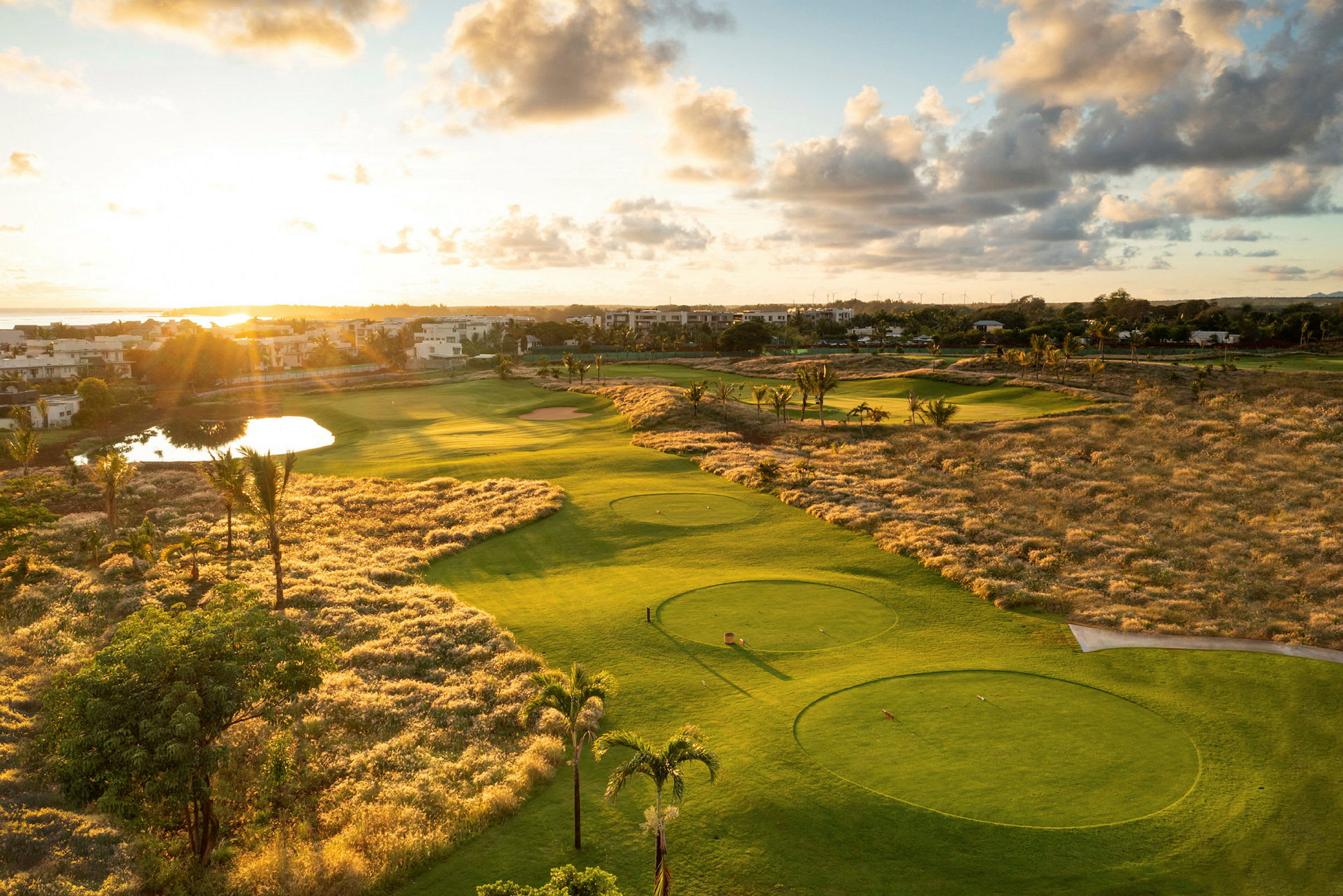 Udsigt over en golfbane i solnedgang med omkringliggende landskab. (AI-genereret tekst)