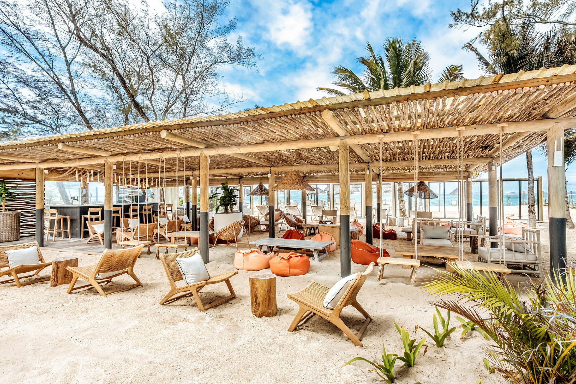 Strandbar med siddepladser og hængekøjer under et trætag. (AI-genereret tekst)