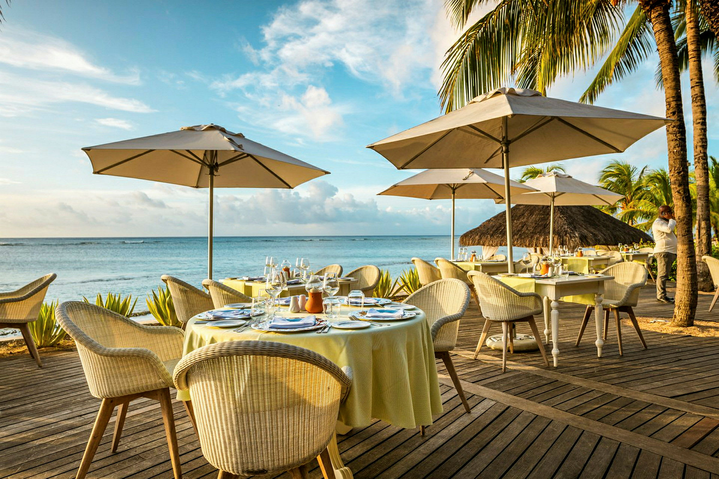 Udendørs terrasse ved havet med dækkede borde og parasoller. (AI-genereret tekst)