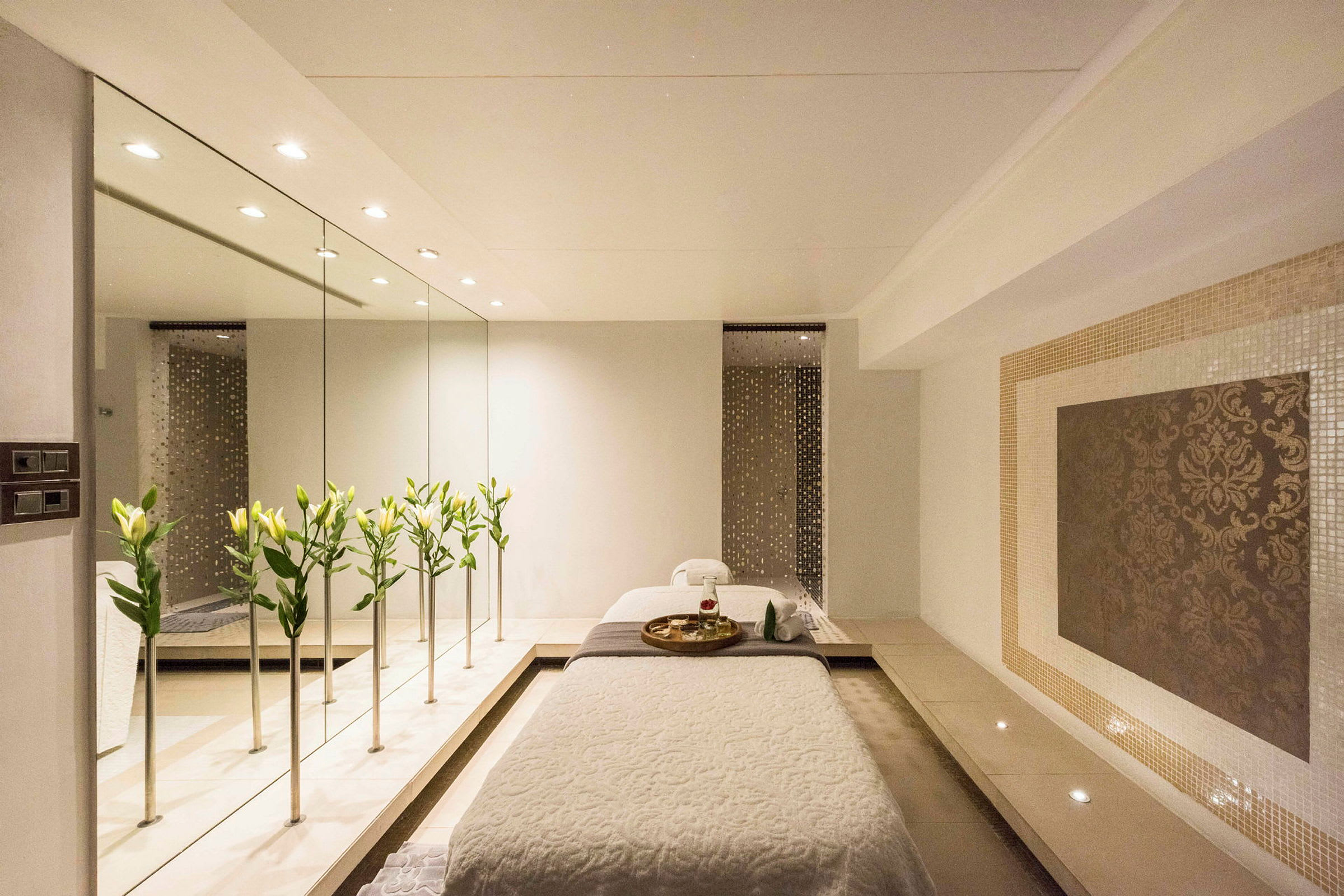 Et stilrent spa-miljø med en massagebriks, blomster og et spejl. (AI-genereret tekst)