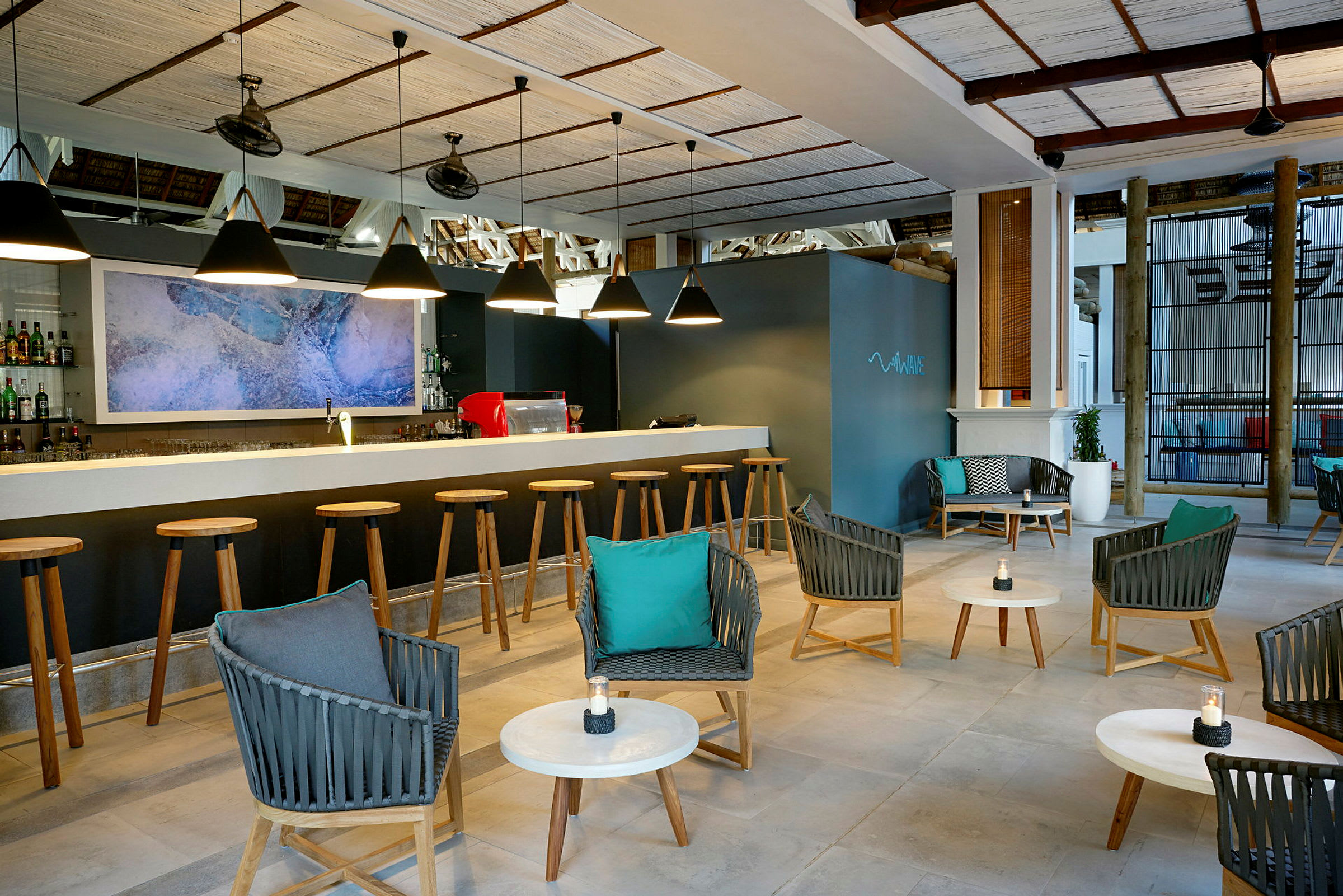 En moderne bar med en række barstole foran en bardisk, hyggelig siddeområde med stole og borde i forgrunden. (AI-genereret tekst)