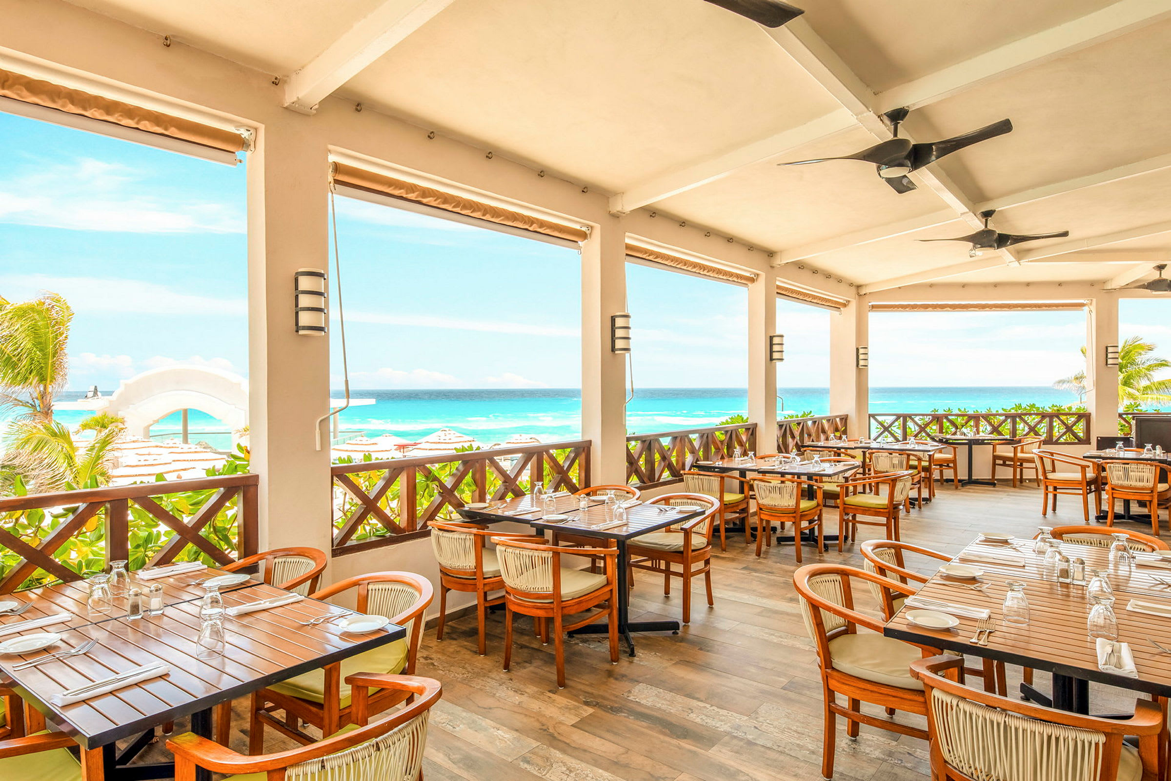 Restaurant med terrasse med borde og stole, udsigt over havet og stranden. (AI-genereret tekst)