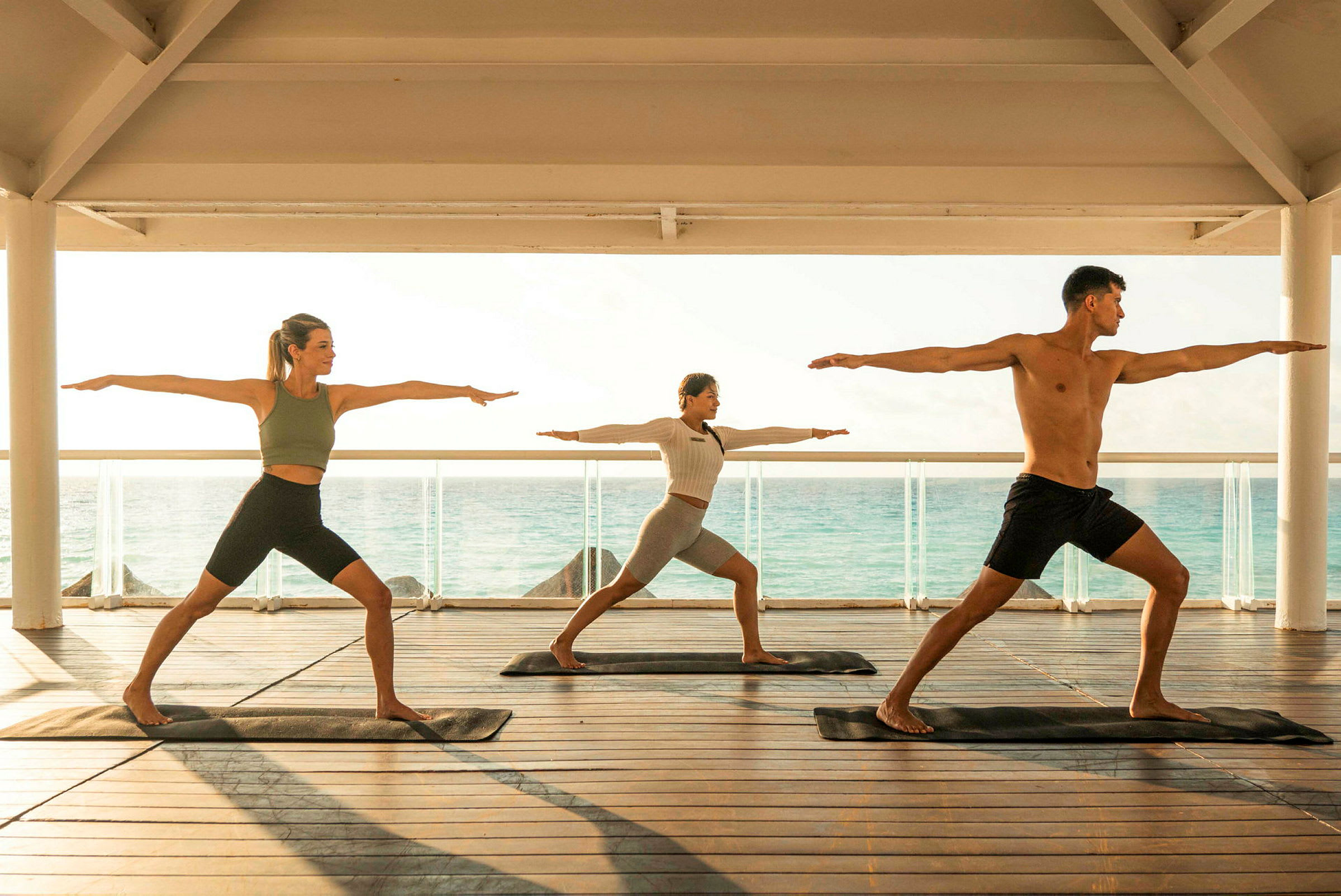 Personer træner yoga på en terrasse med havet i baggrunden. (AI-genereret tekst)