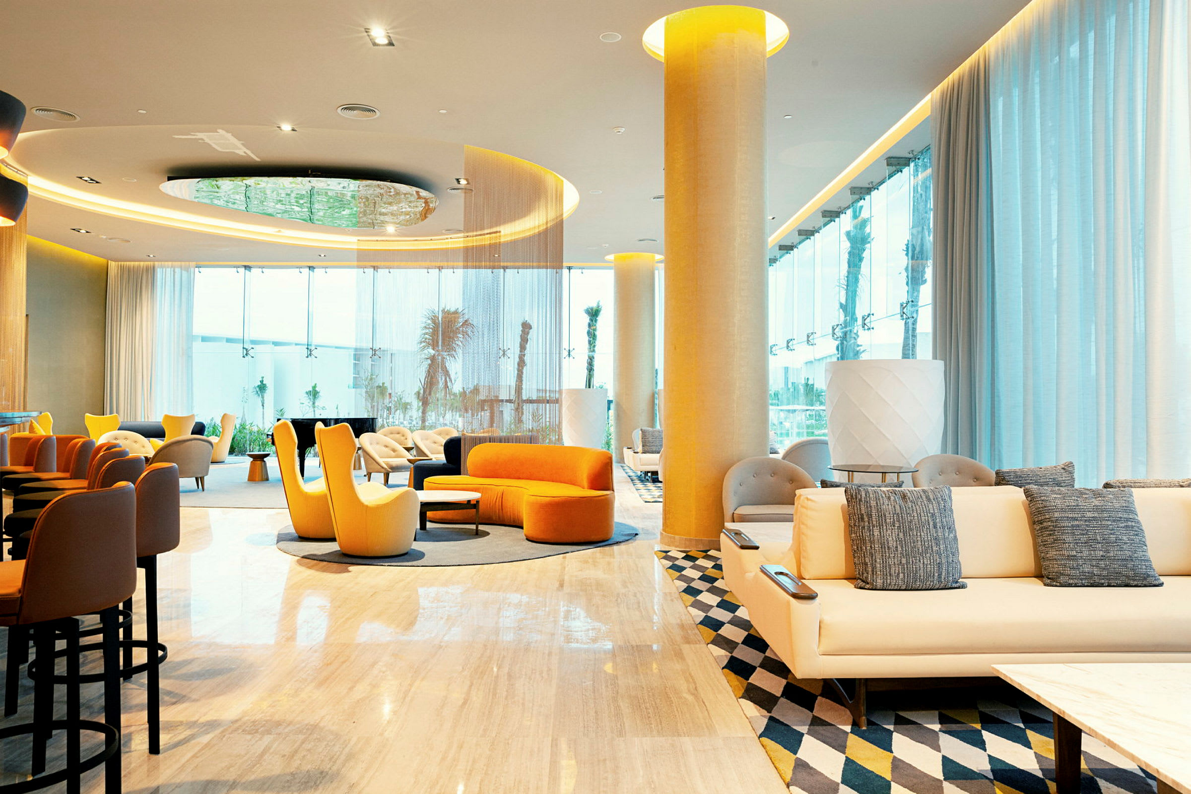 Interiør af et moderne hotellobbyområde med farvestrålende siddepladser og store vinduer. (AI-genereret tekst)