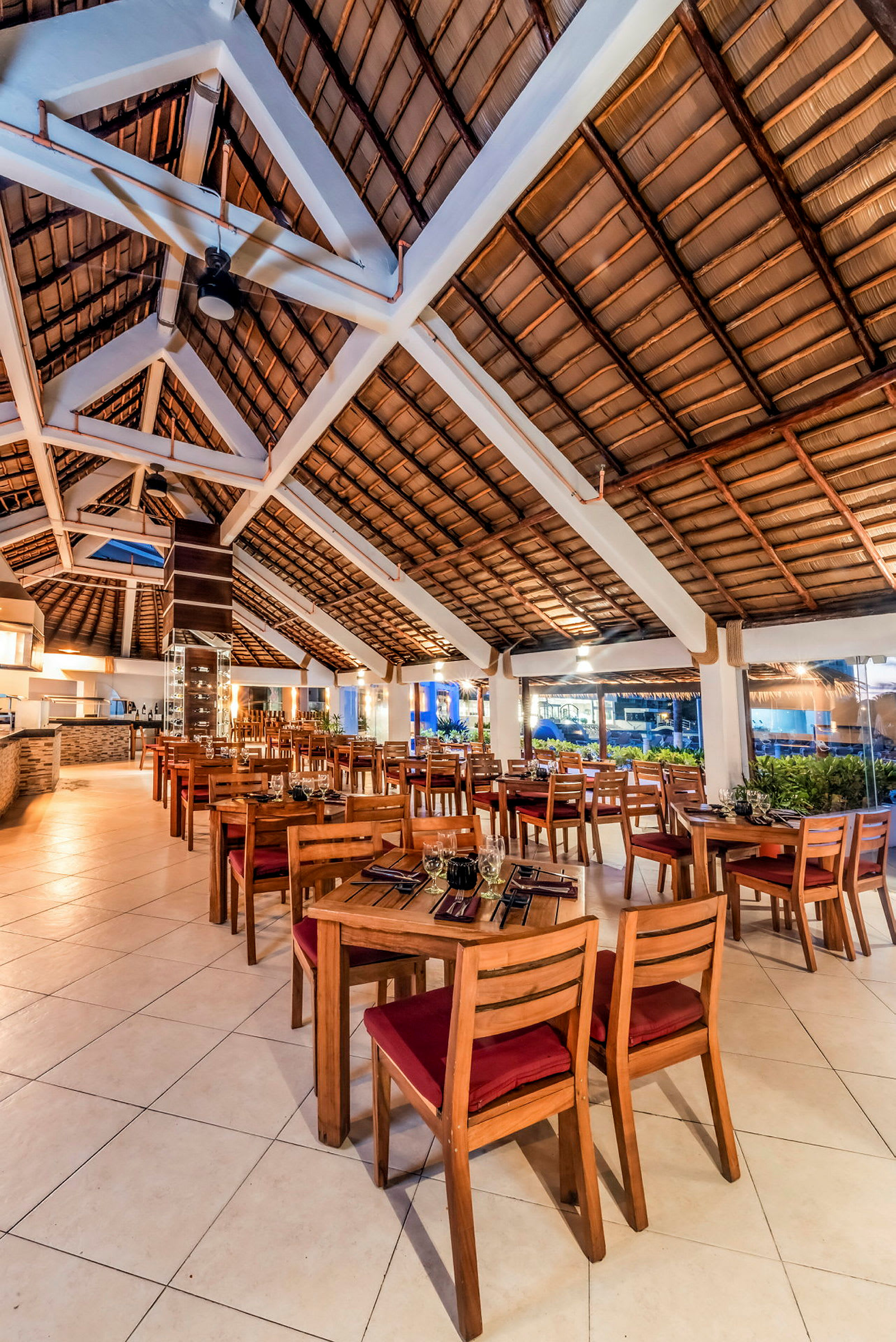 Restaurant med træborde og stole placeret på et lyst gulv, under et højt loft med loftsbjælker. (AI-genereret tekst)