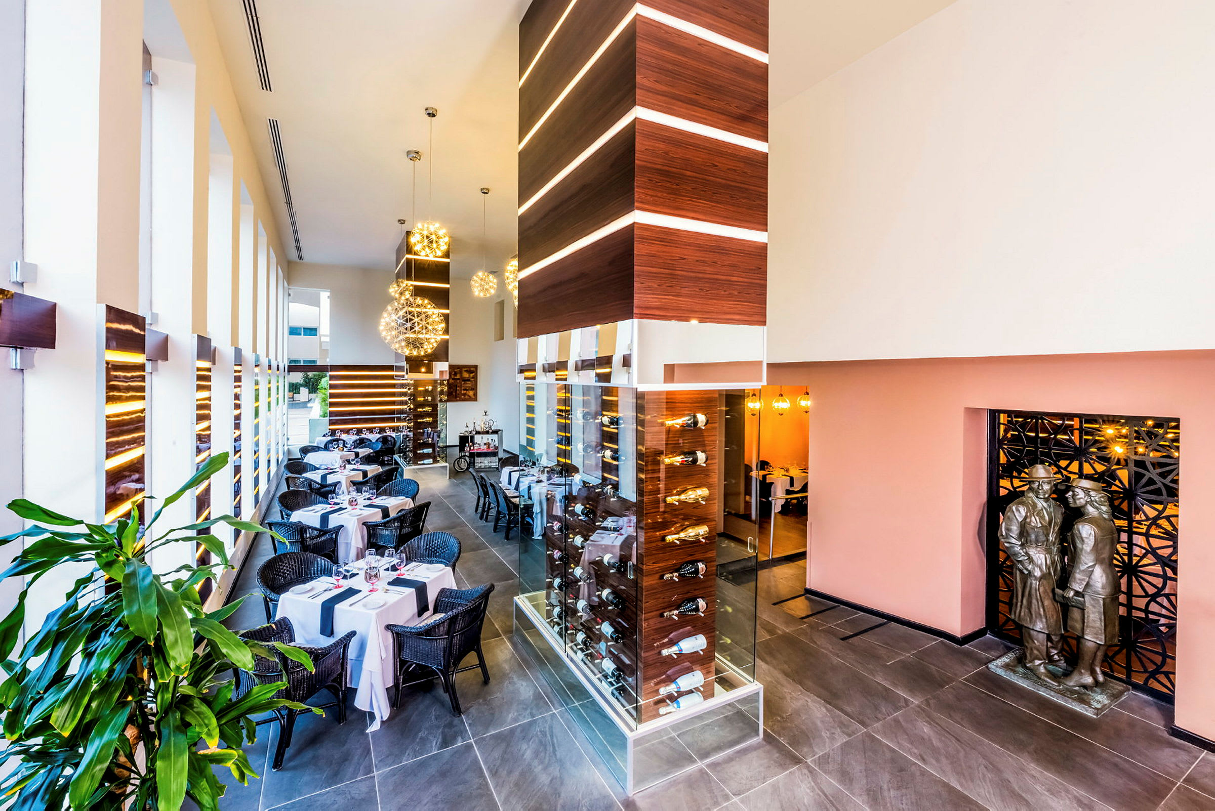 Interiør af en moderne restaurant med dækkede borde, elegante dekorationer og et glasskab med flasker. (AI-genereret tekst)