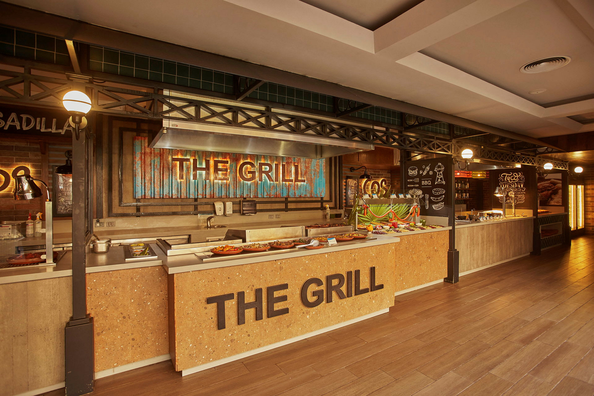 Buffetområde med en grillstation mærket 'The Grill' og madopstillinger. (AI-genereret tekst)