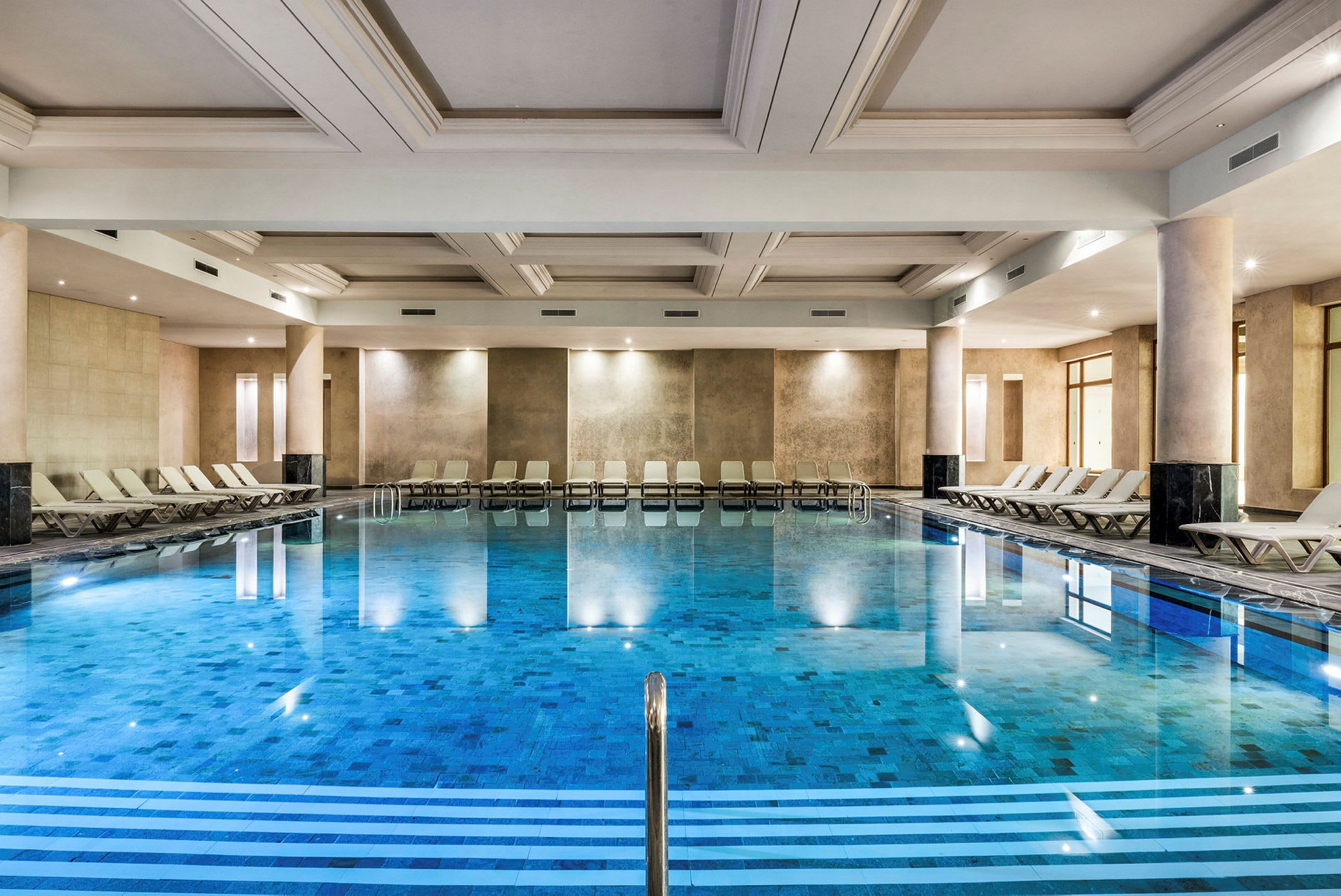 En indendørs pool med liggestole ved siderne. (AI-genereret tekst)