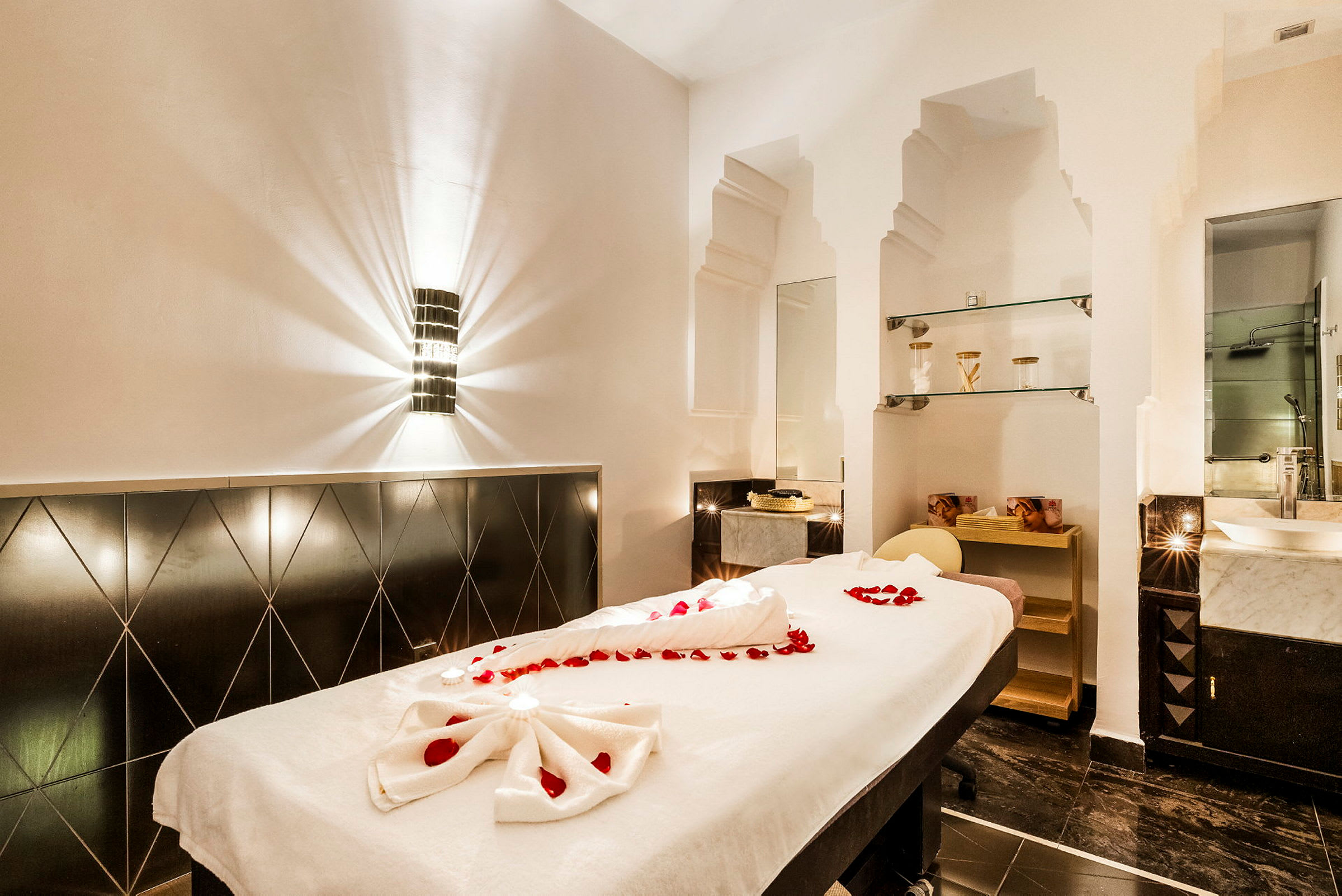 Et spa-rum med massagebænk dekoreret med røde rosenblade. (AI-genereret tekst)