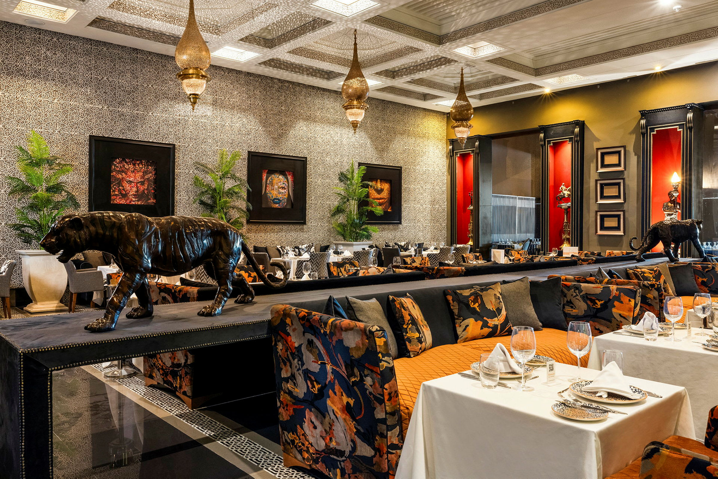 Billede af en elegant restaurant med eksotisk tema, inklusive dekorationer med leopardstatuer, forgyldte lamper og farverige møbler. (AI-genereret tekst)