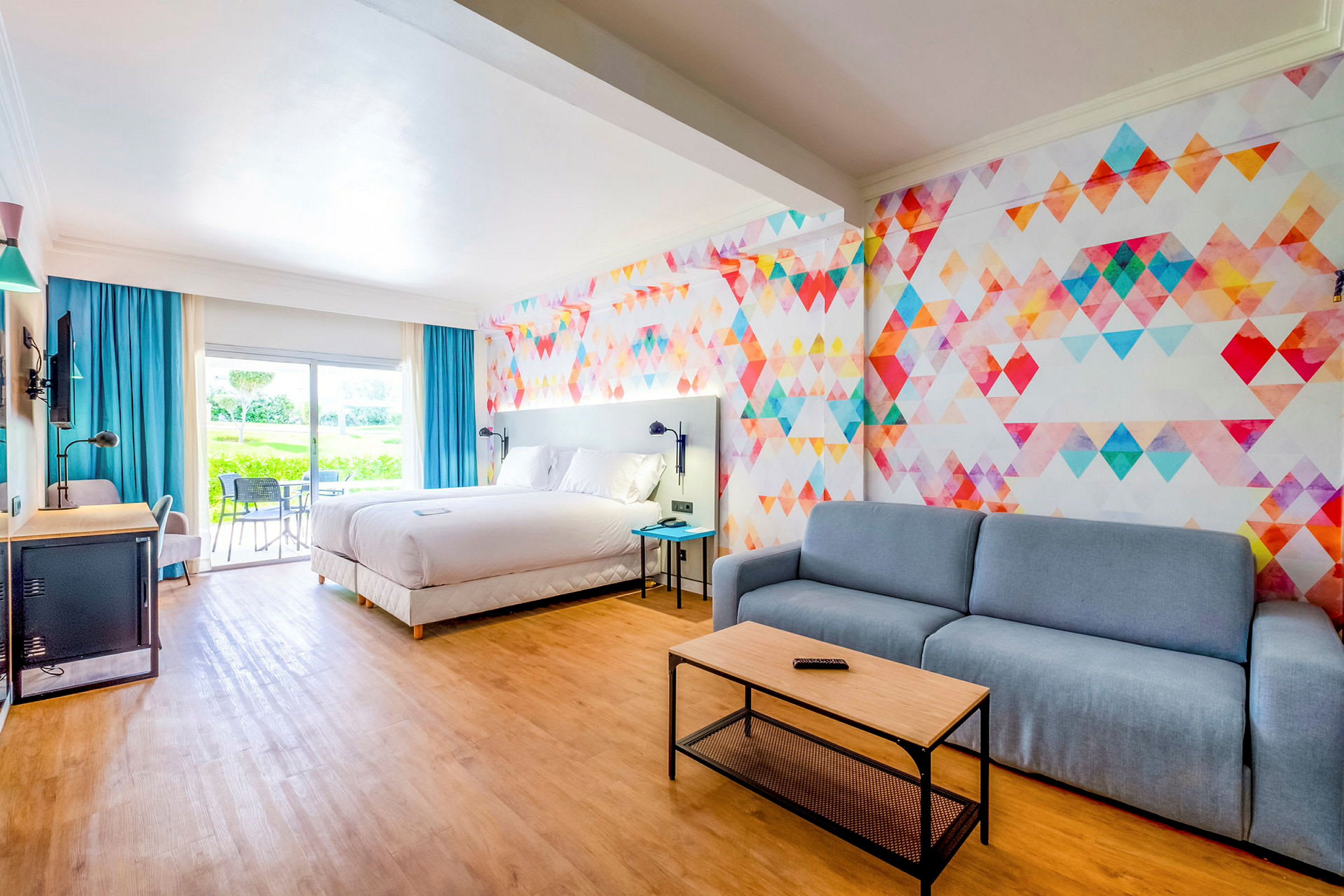 Hotelværelse med stor seng, siddeområde og farverigt vægdesign. (AI-genereret tekst)