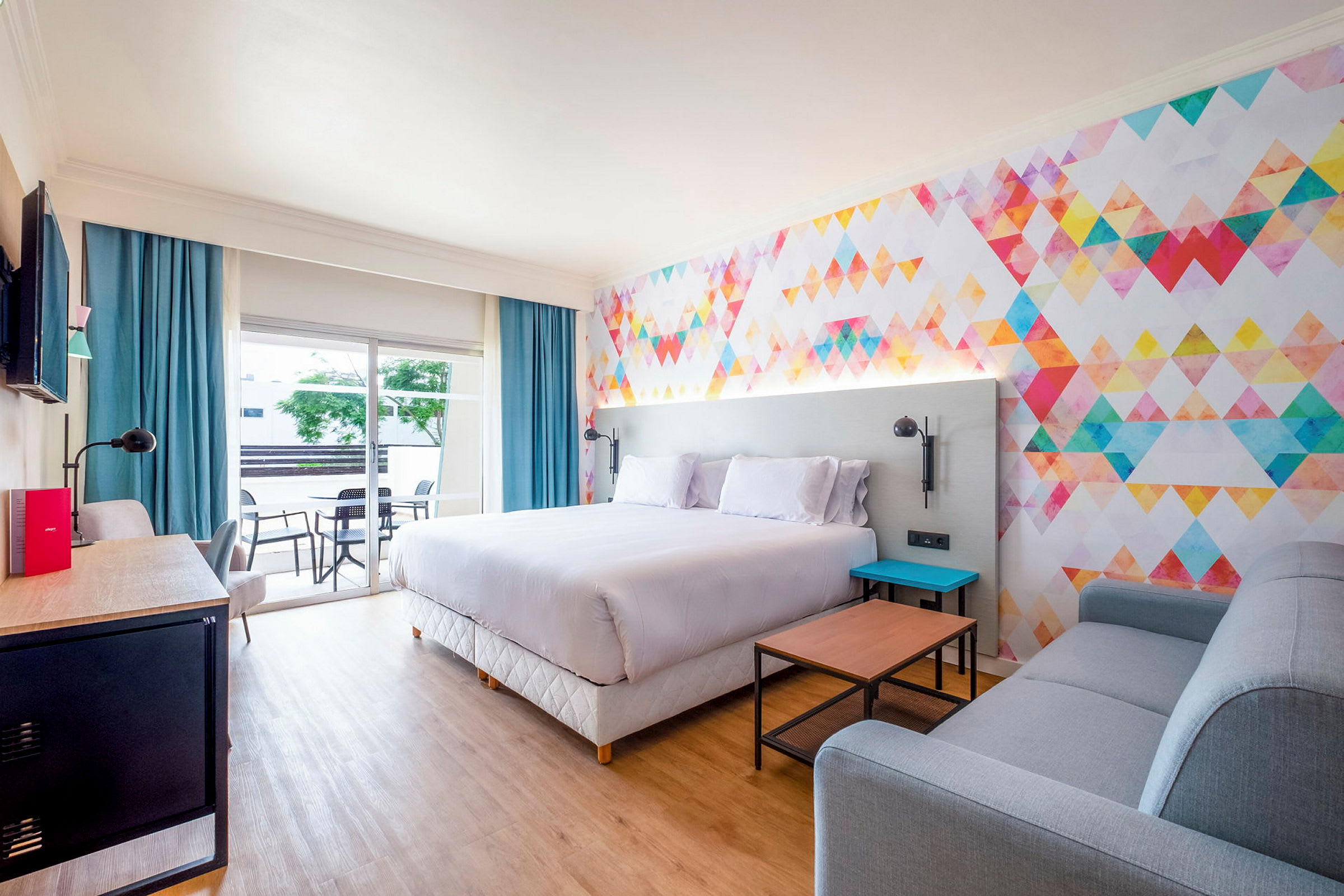 Moderne hotelværelse med farverigt vægdesign og komfortable møbler. (AI-genereret tekst)