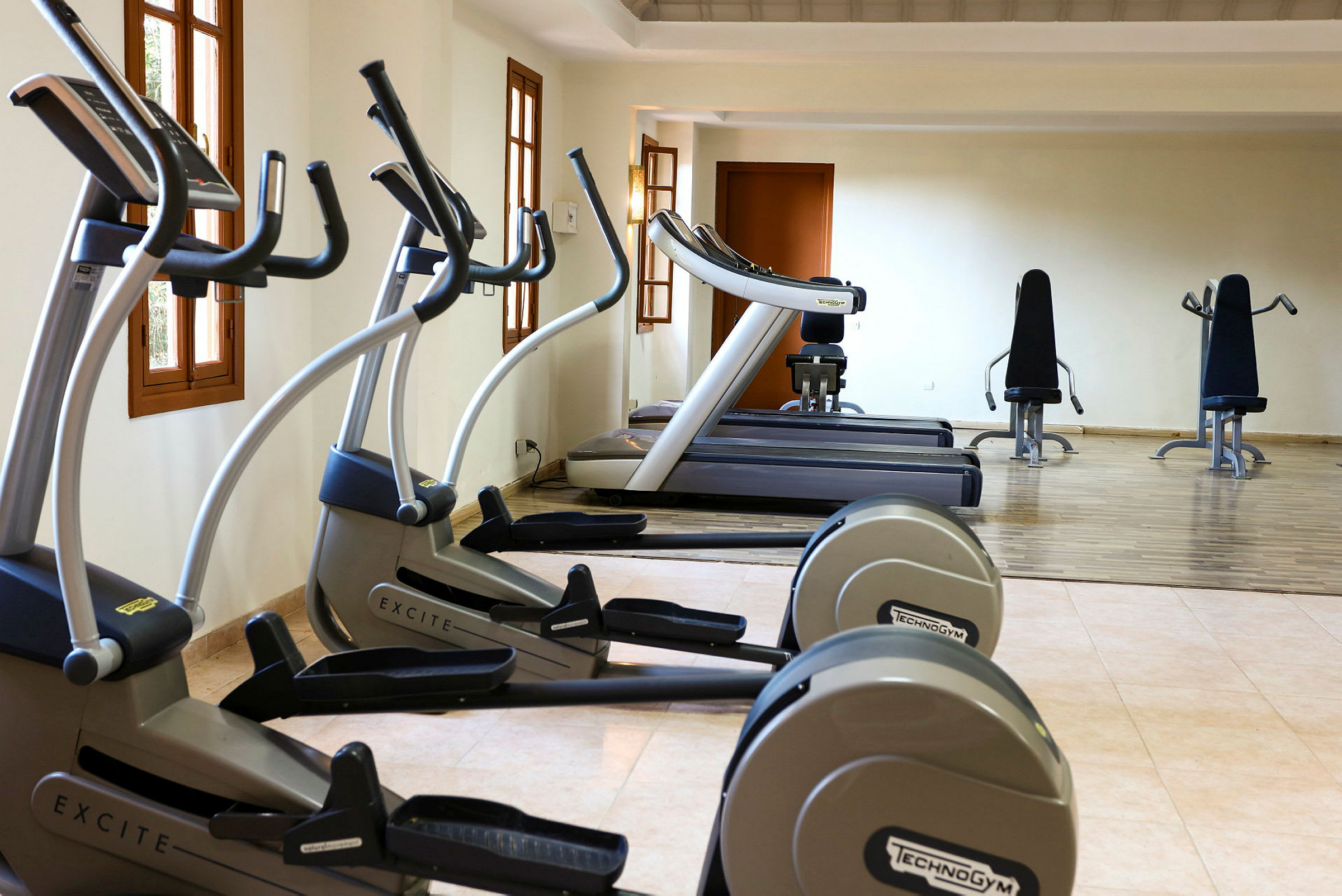 Billede af et fitnesscenter med træningsmaskiner, herunder løbebånd og motionscykler. (AI-genereret tekst)