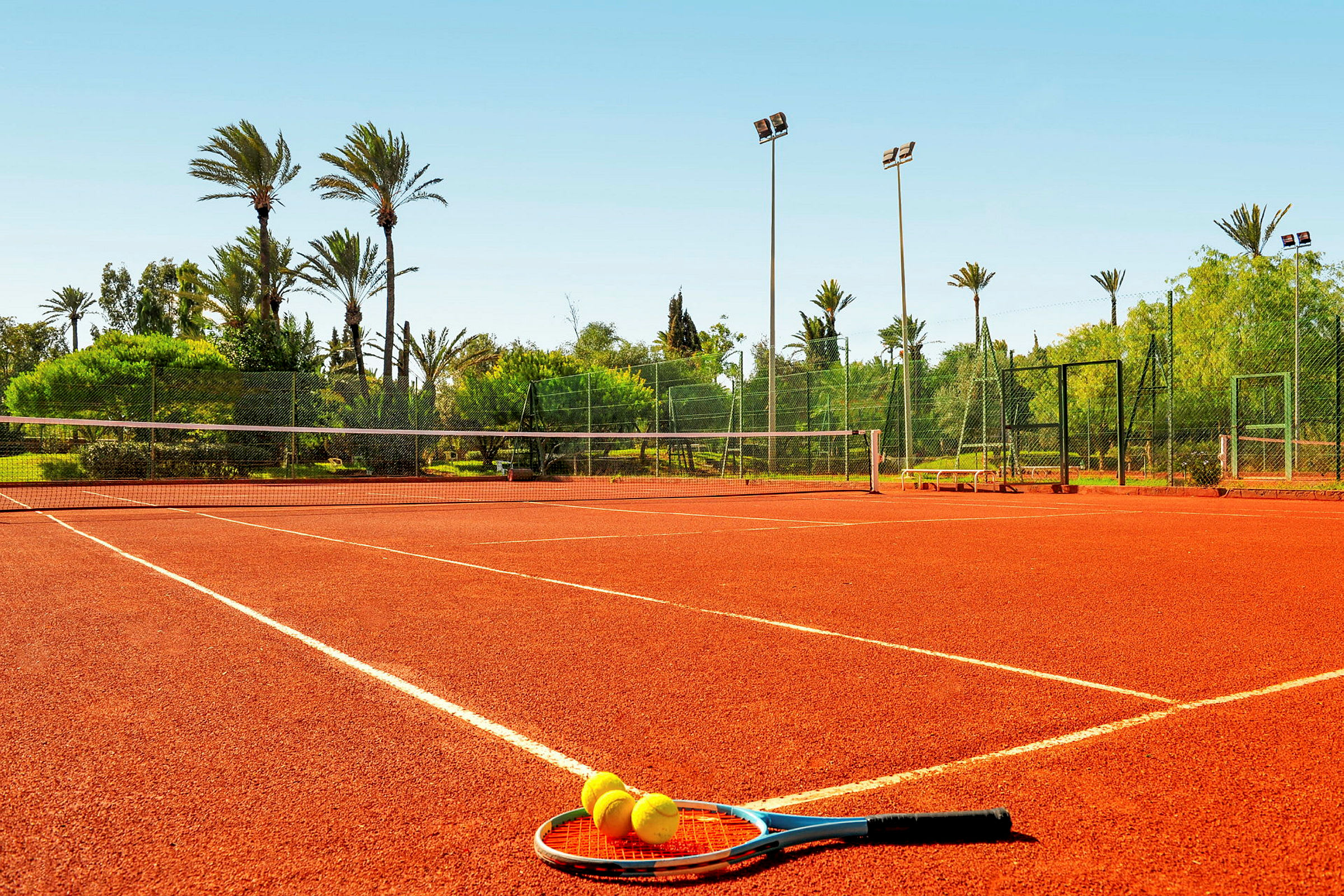 Tennisbane med ketcher og bolde på jorden. (AI-genereret tekst)