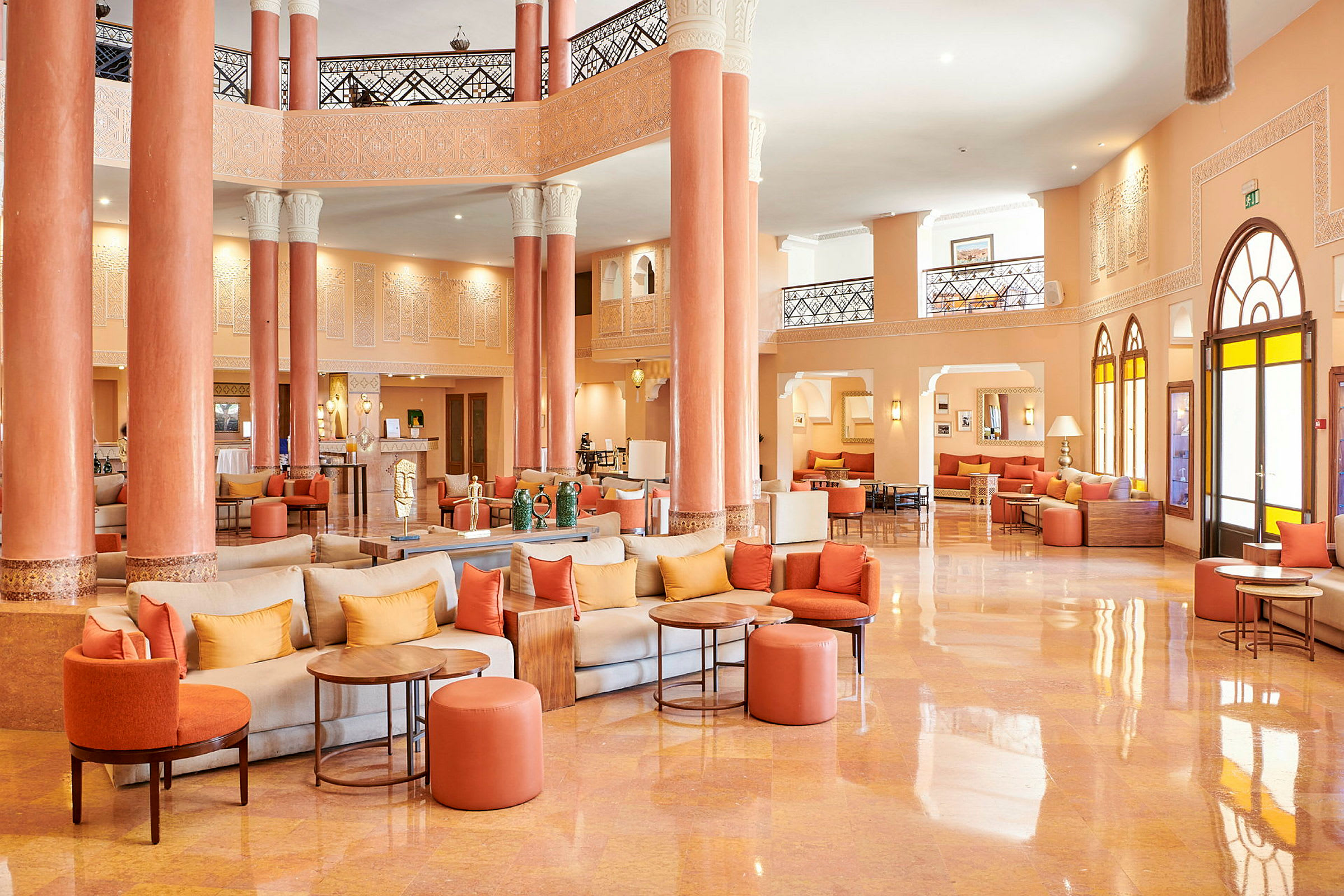 Hotellobby med orange og beige farver, siddegrupper og søjler. (AI-genereret tekst)