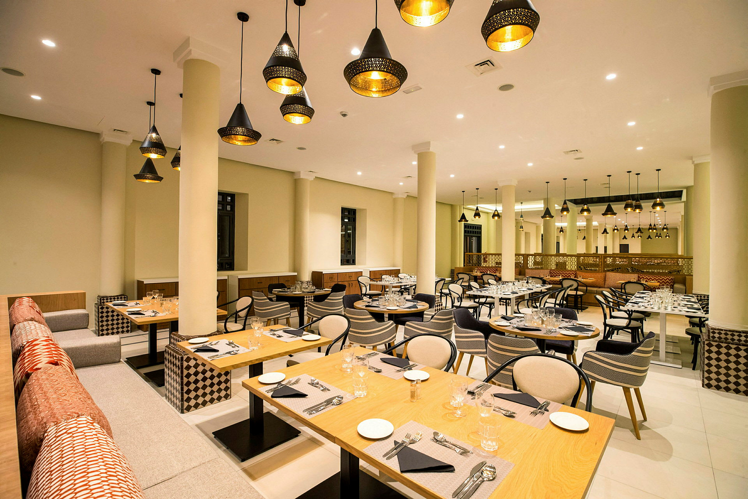Restaurant med dekorative lamper, dækkede borde og siddepladser. (AI-genereret tekst)