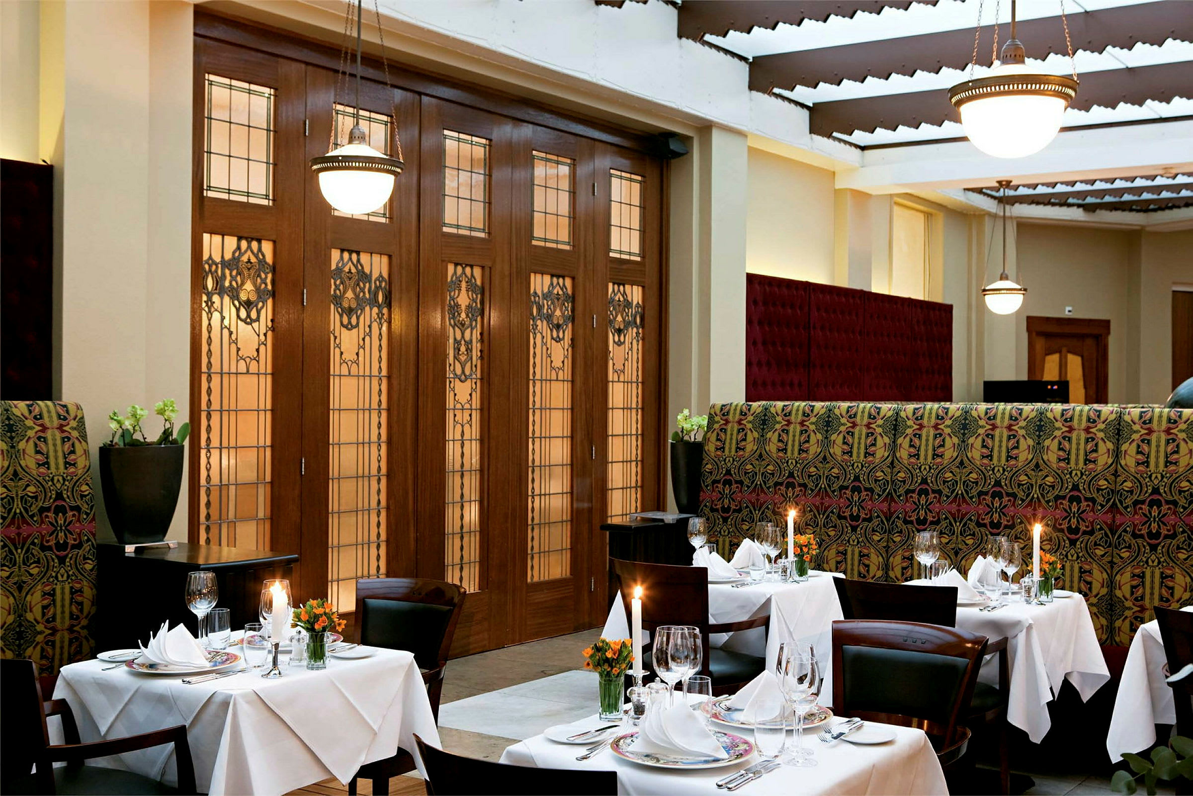 En elegant restaurant med dækkede borde, lysestager og dekorativ indretning. (AI-genereret tekst)