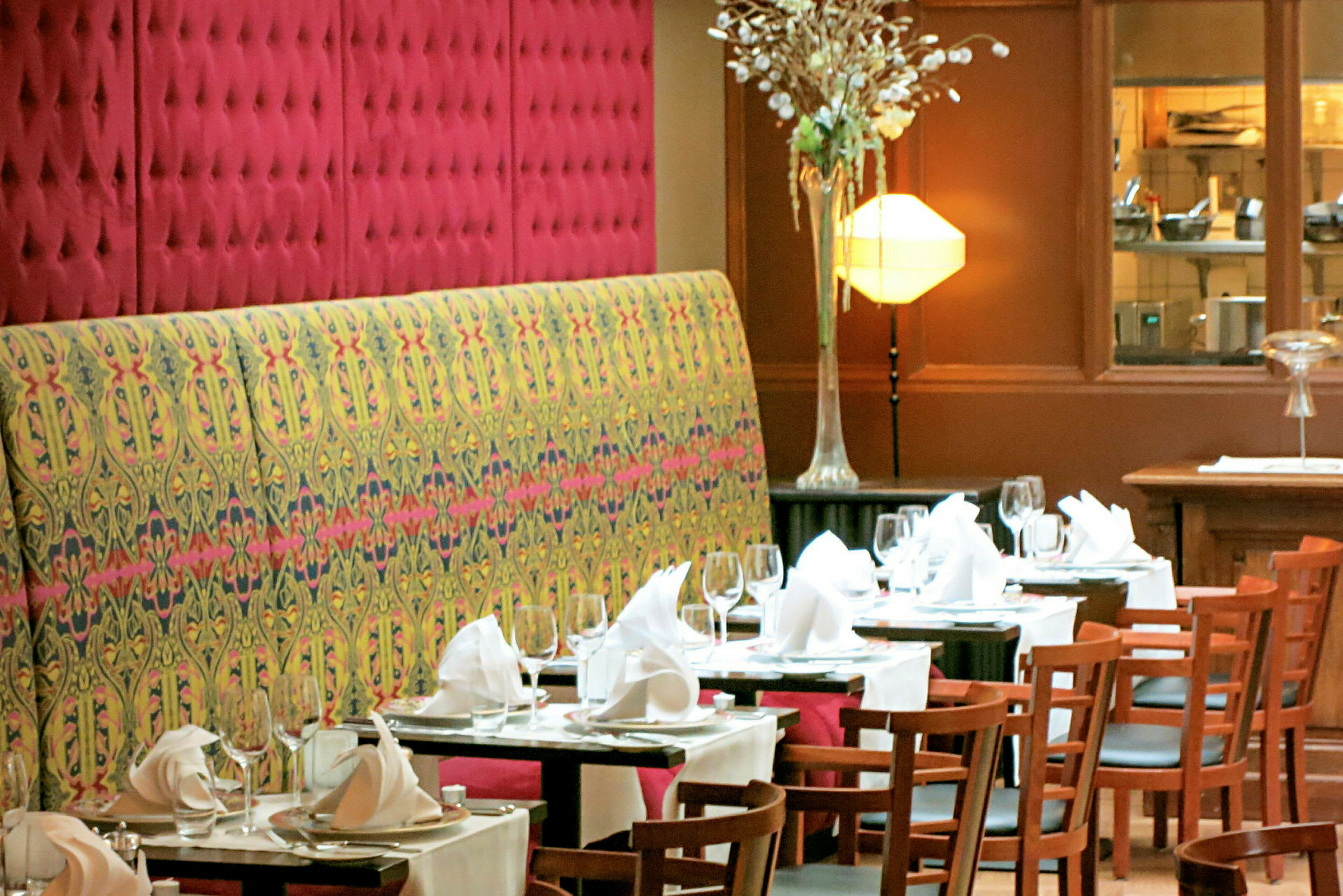 En restaurantinteriør med dækkede borde med hvide duge, glas, tallerkener og foldede servietter. (AI-genereret tekst)