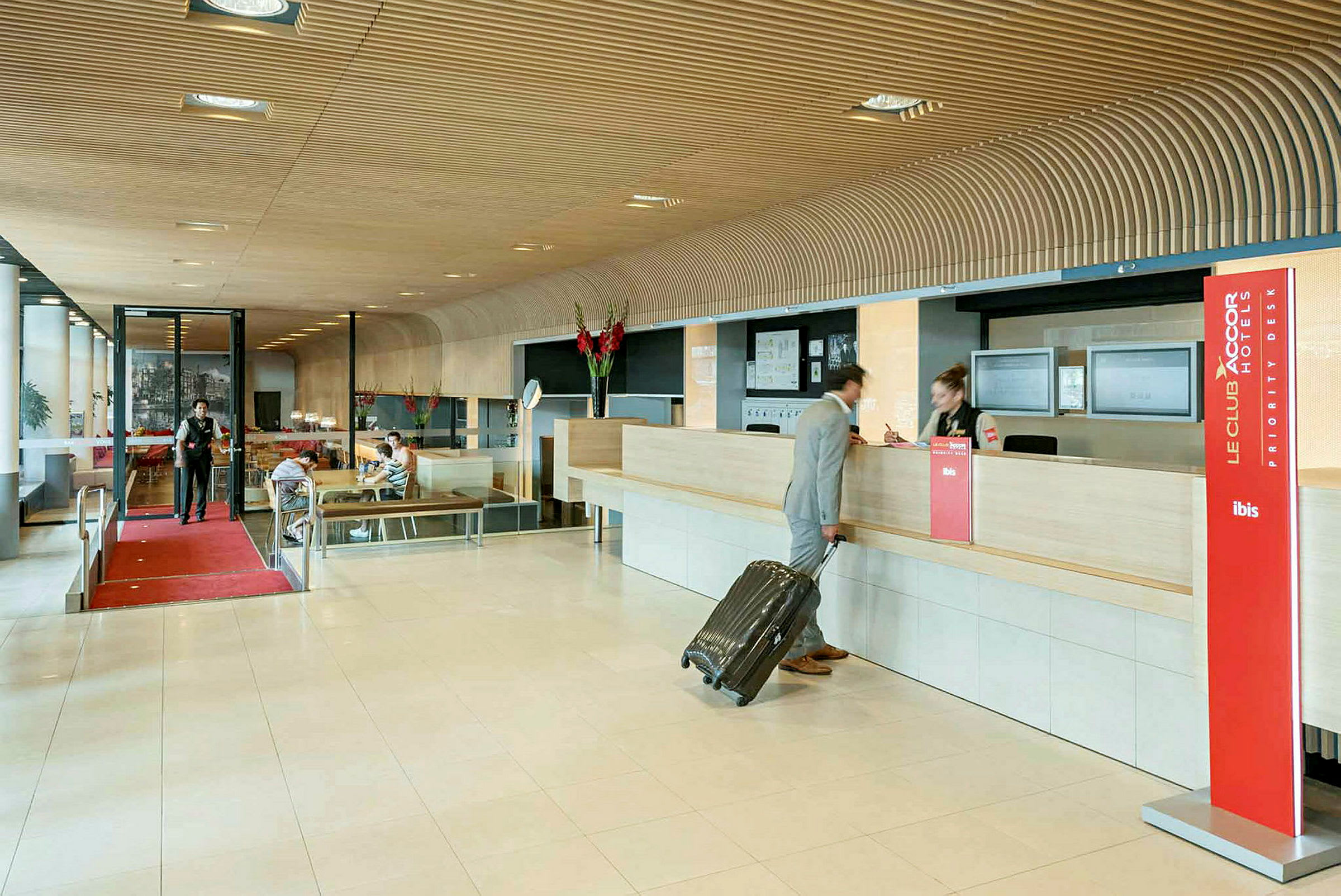Hotellobby med reception, en person med kuffert tjekker ind. (AI-genereret tekst)